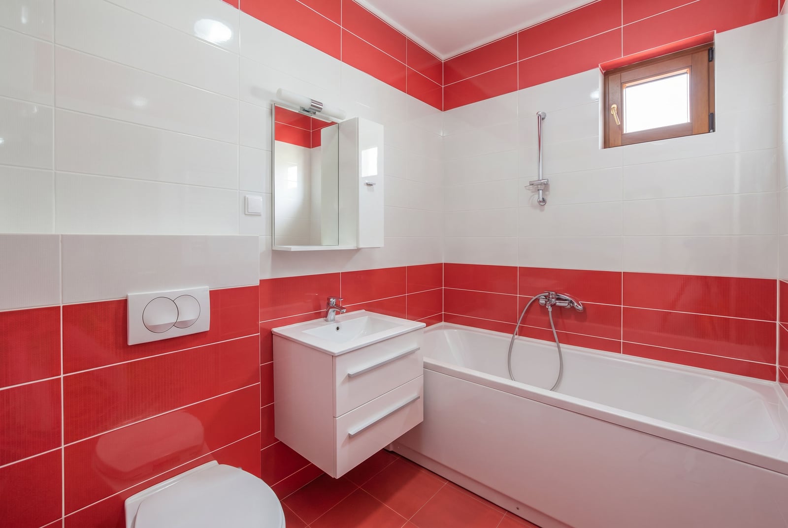 Bathroom with red and white tiles, a bathtub, and a vanity unit in an apartment, Becici residential complex, Montenegro.