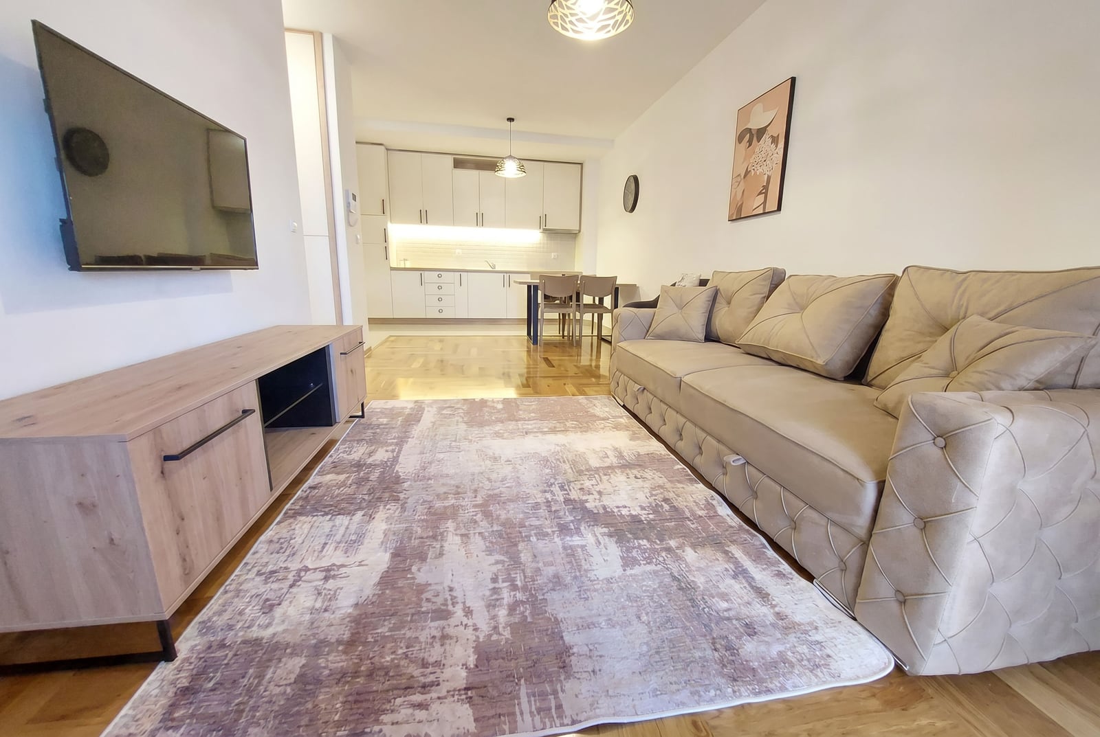 Modern living room with a beige sofa and kitchen in an apartment, Rafailovici, Montenegro. Parquet flooring and stylish interior.