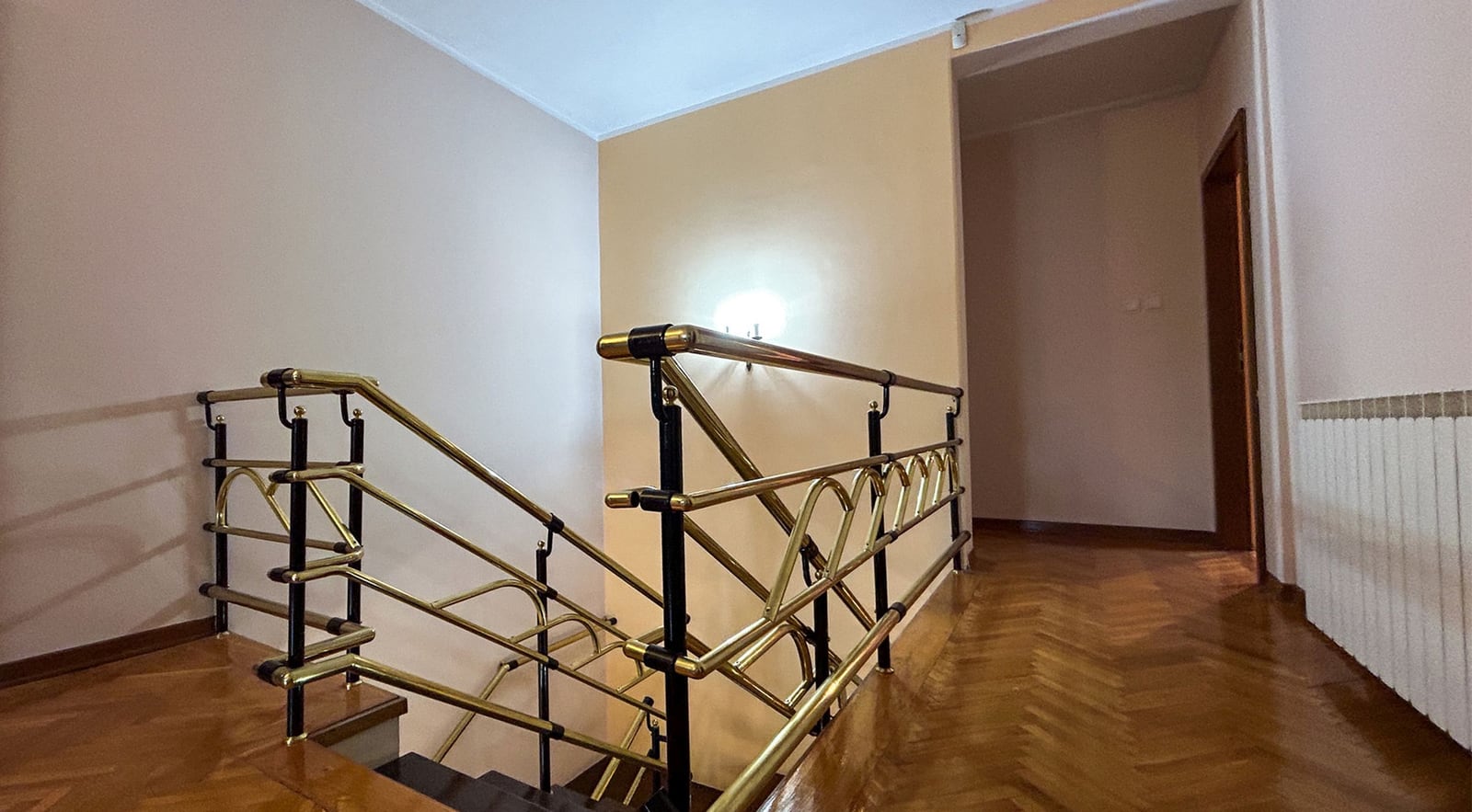 Staircase with golden railings in the interior of a villa in Dobrota, Montenegro: parquet flooring and light wall finishes.