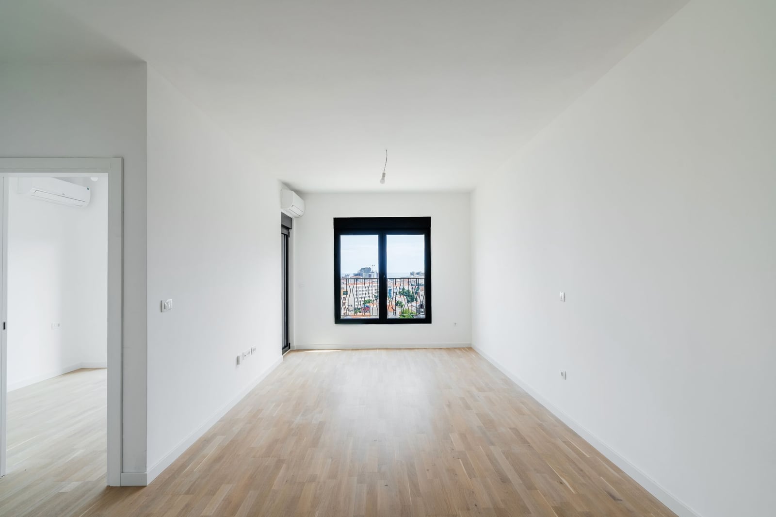 Bright living room with parquet flooring in a new residential complex in Budva, Montenegro: window view and modern wall finishes.