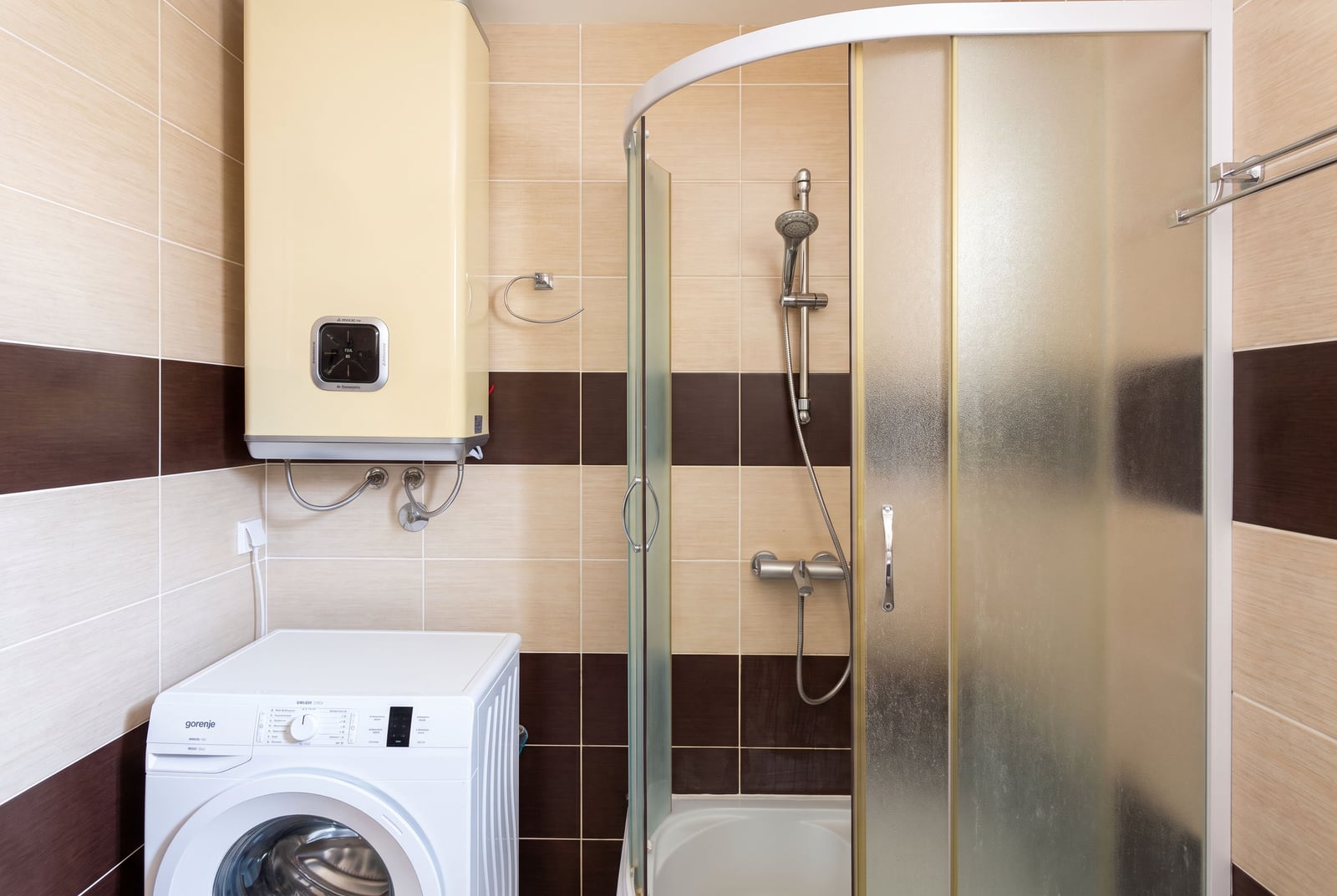 Modern bathroom with a shower cabin, water heater, and washing machine in an apartment in Tivat, Montenegro
