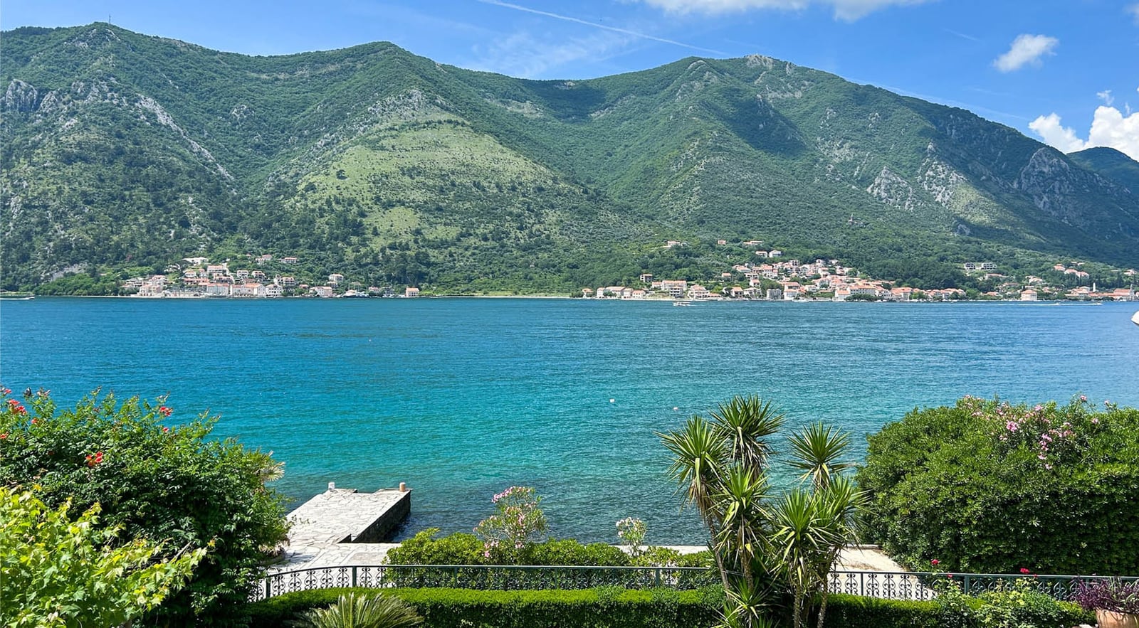 Panoramic view of Kotor Bay and the mountains from the villa terrace in Dobrota, Montenegro: private pier and blooming garden.