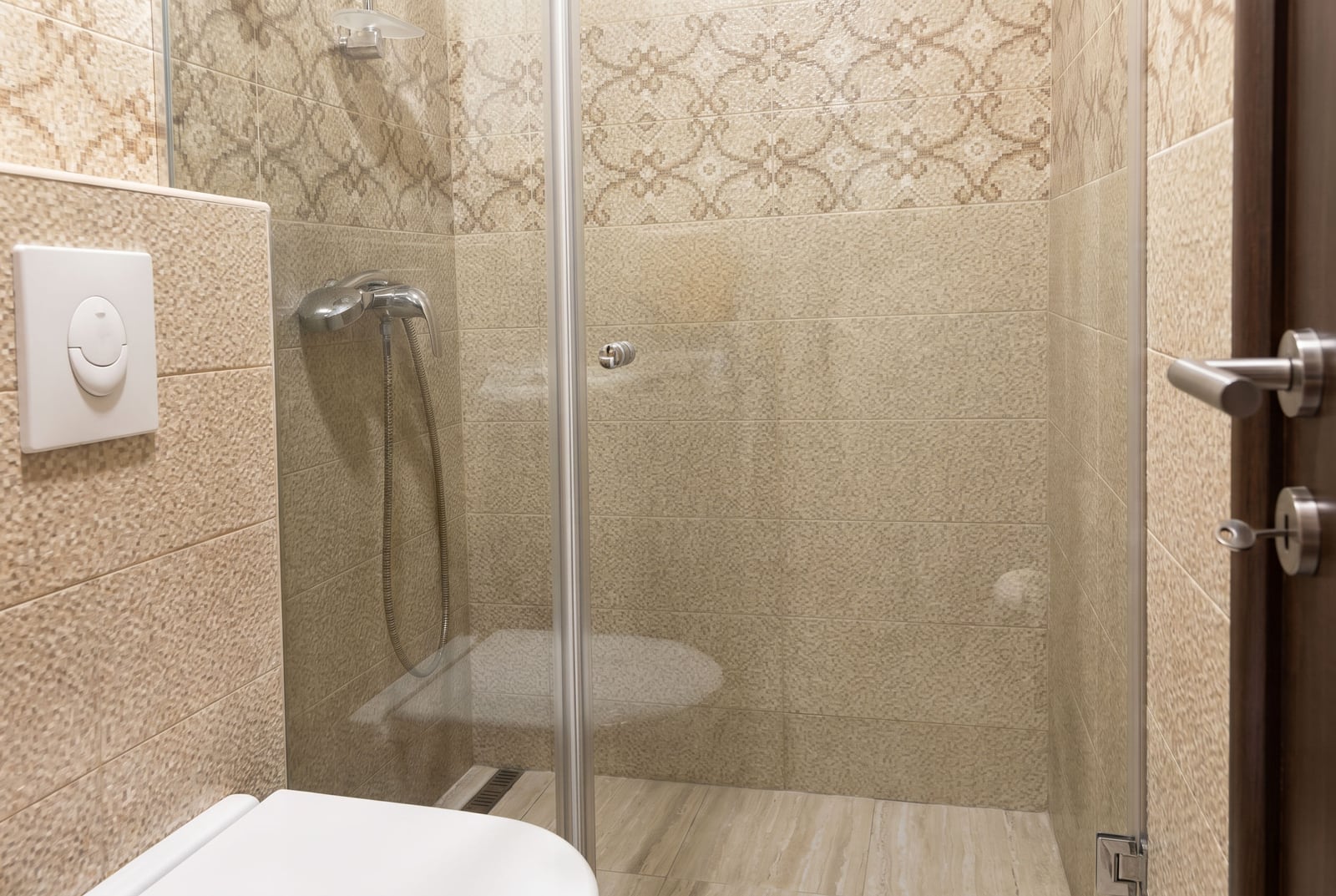 Modern bathroom with a shower cabin and beige tiles in an apartment for sale, Budva, Montenegro.