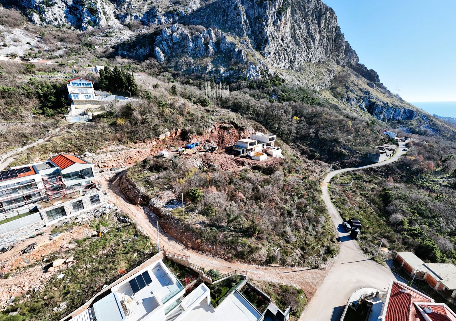 Villas under construction on a land plot in Blizikuće, Montenegro: panoramic view of the mountains and the properties under construction.