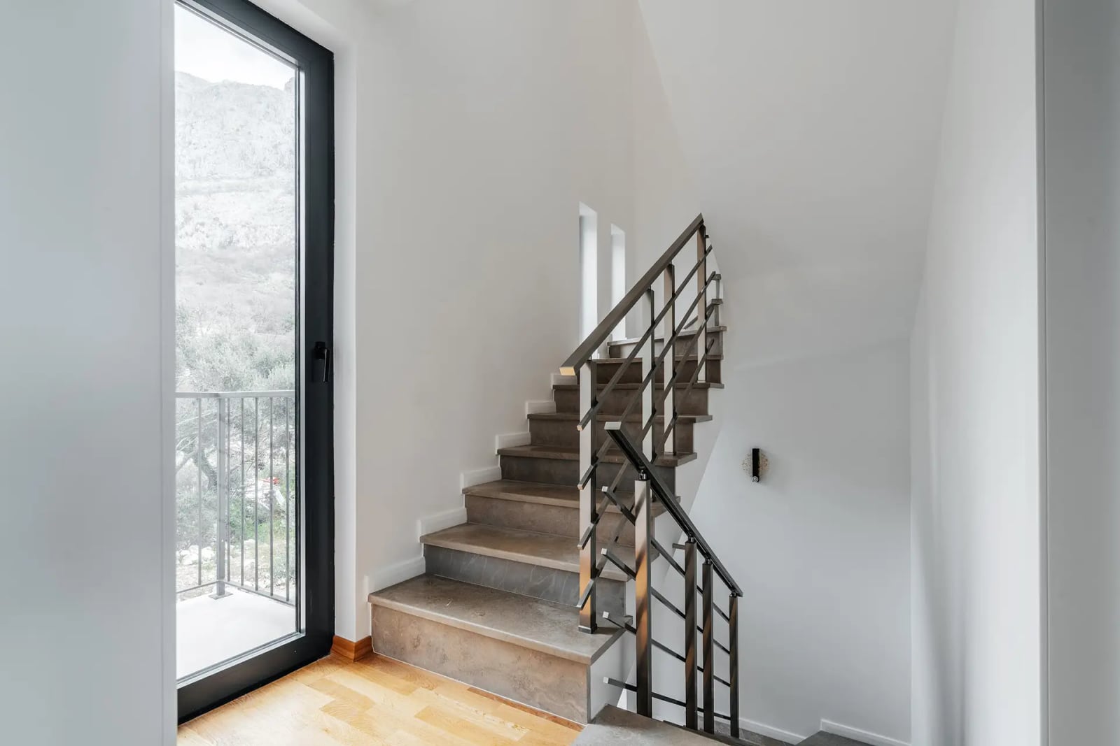 Modern staircase with stone steps and a panoramic window in a villa in Reževići, Montenegro.