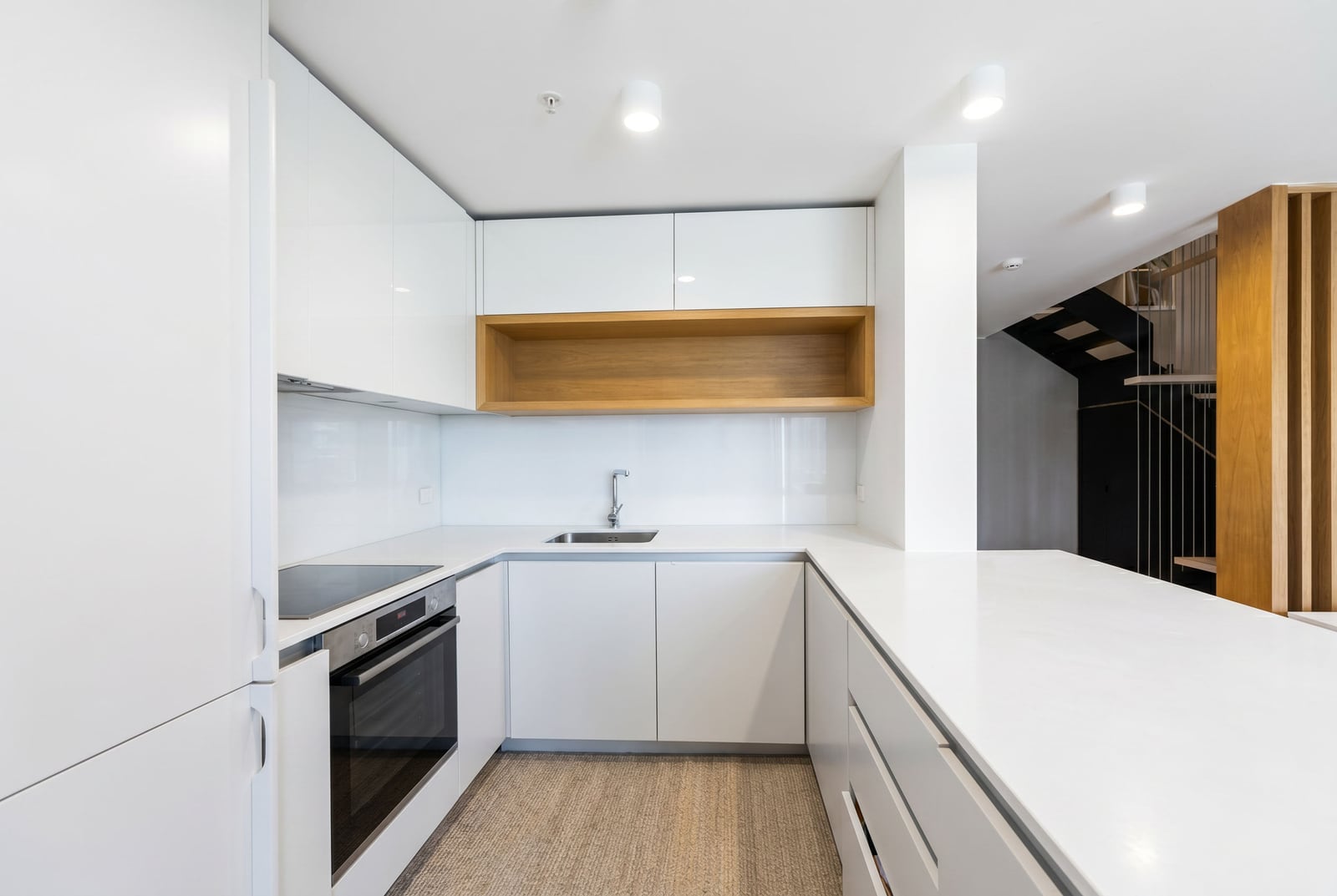 Modern white kitchen with wooden shelves in an apartment, Budva, Montenegro. Interior with built-in appliances.