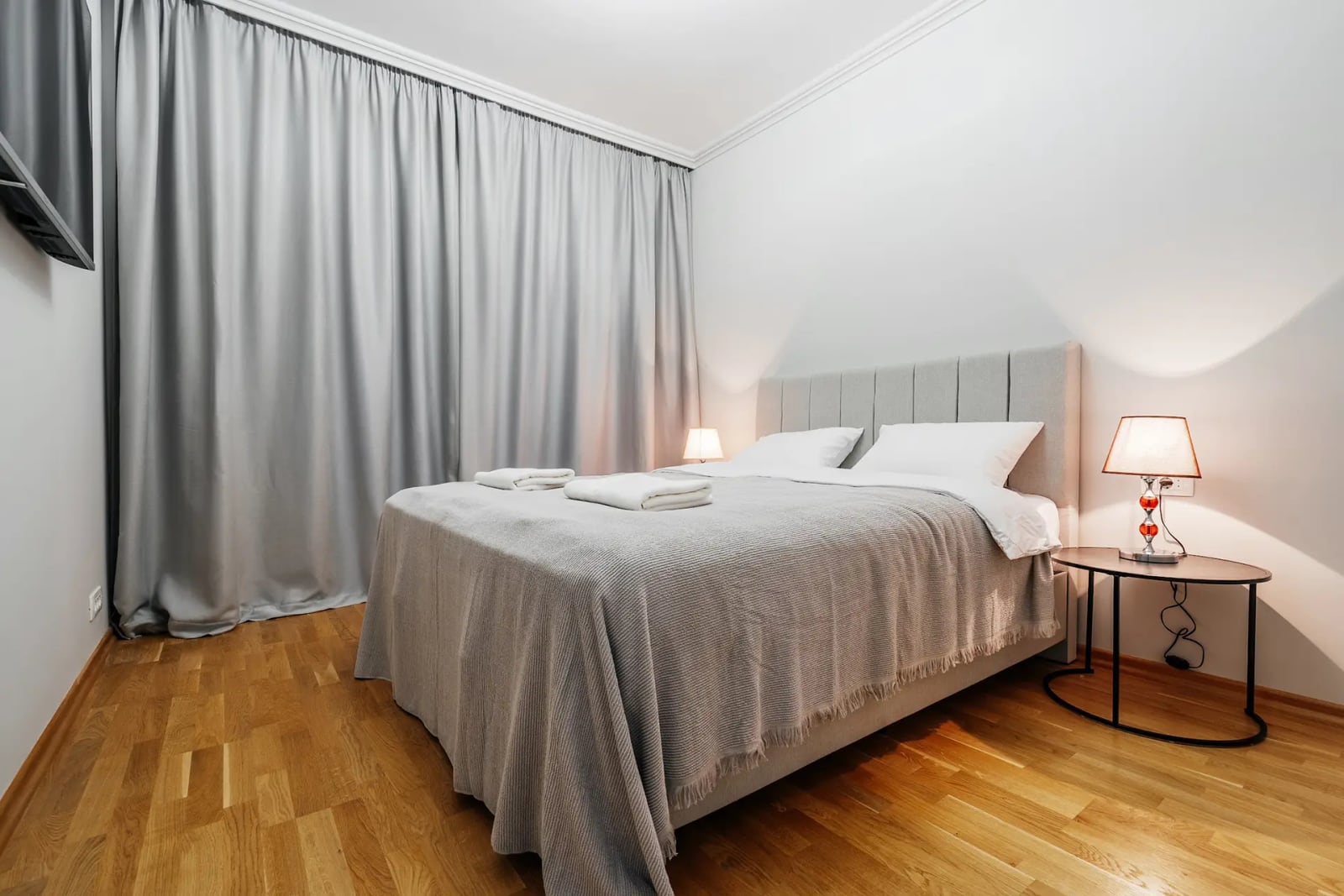 Cozy bedroom with a double bed in a villa in Reževići, Montenegro: bright interior, parquet flooring, and grey curtains.