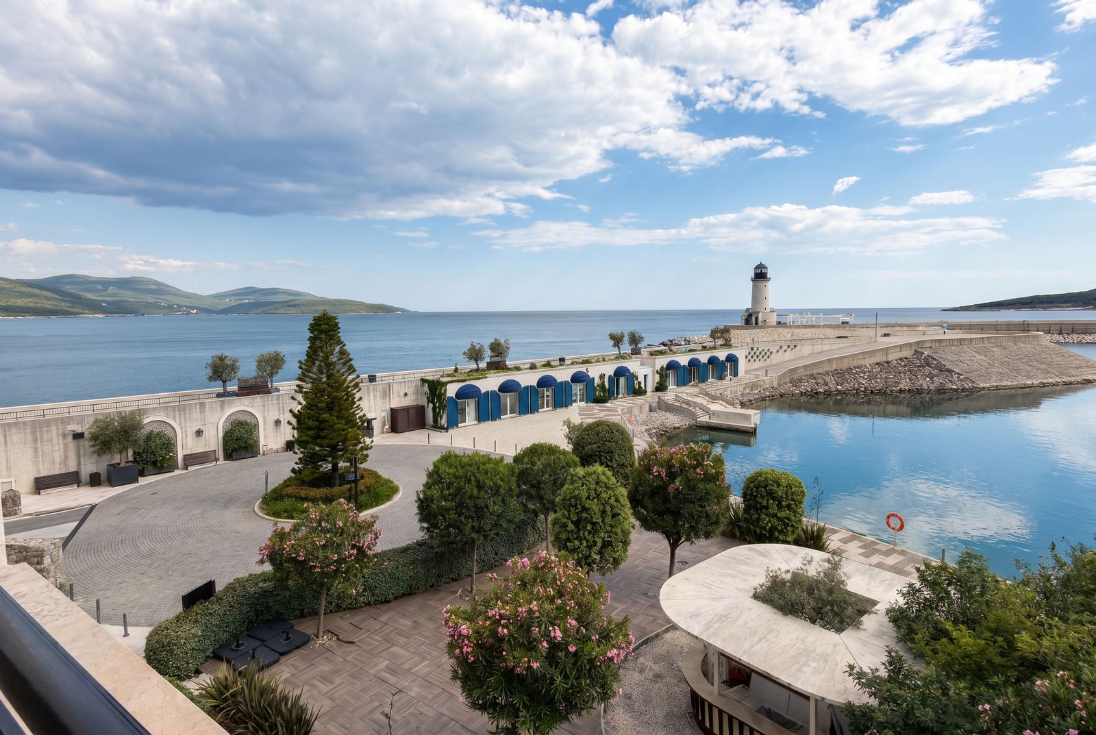 View of the promenade and lighthouse in Luštica Bay, Montenegro: landscaped grounds with scenic design and the sea.