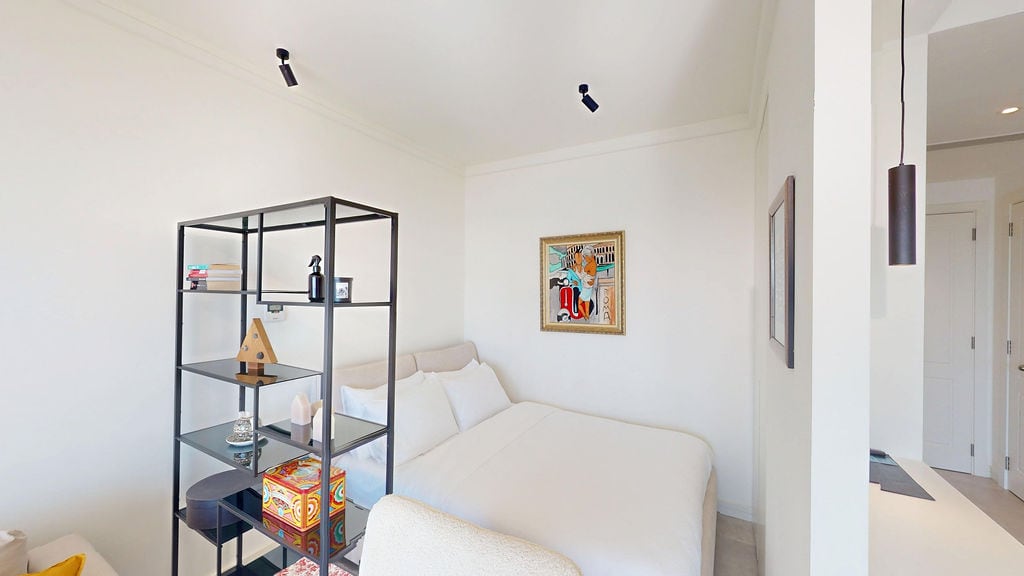 Modern bedroom in an apartment in Luštica, Montenegro: double bed, stylish shelving unit, and light-colored finishes.