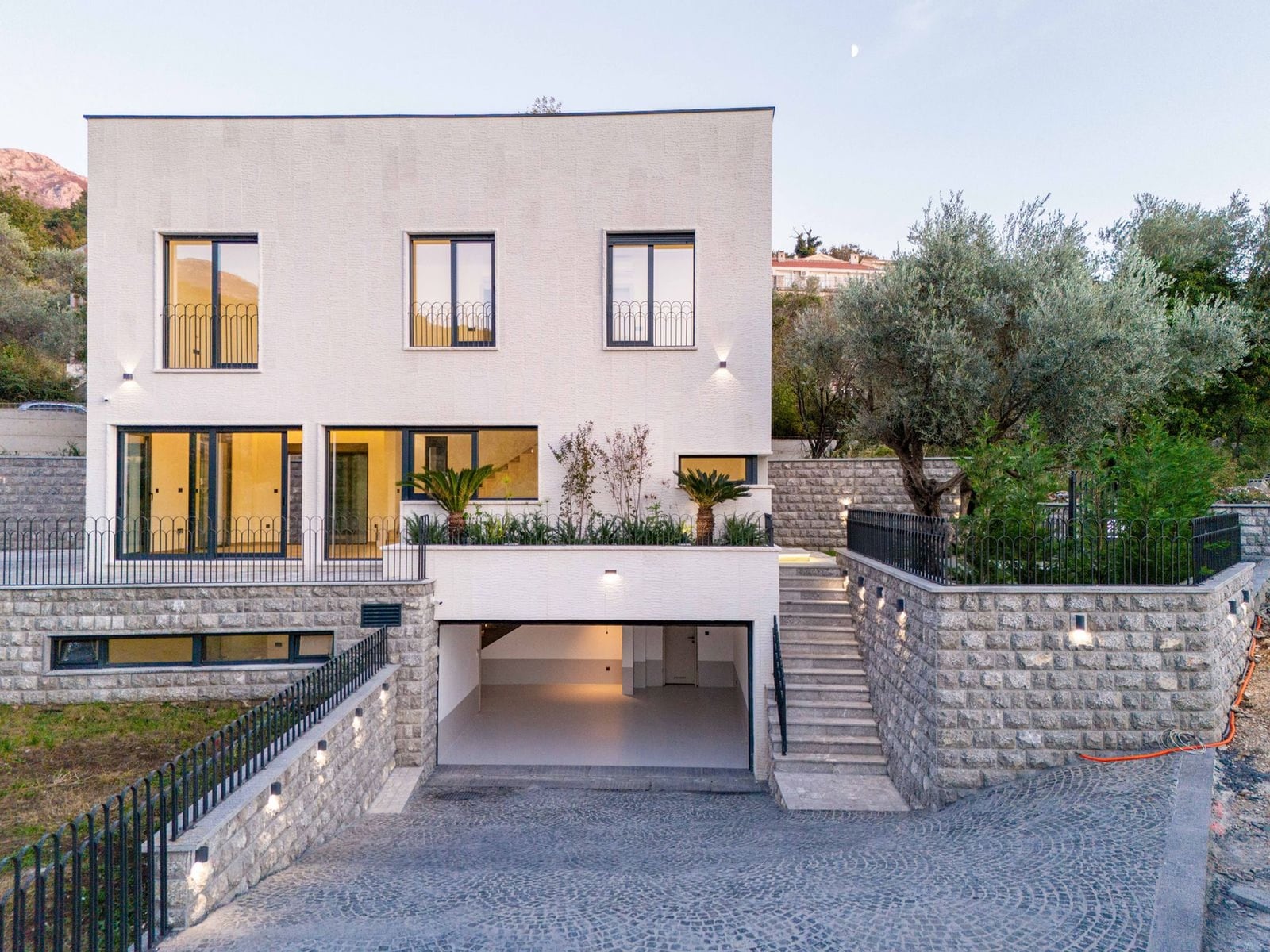 Modern villa in Kamenovo, Montenegro: facade with panoramic windows, terrace, landscape design, and garage.