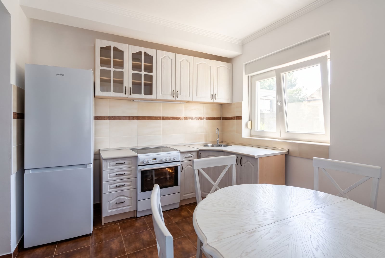 Bright kitchen with furniture, stove, refrigerator, and dining area in an apartment in Tivat, Montenegro