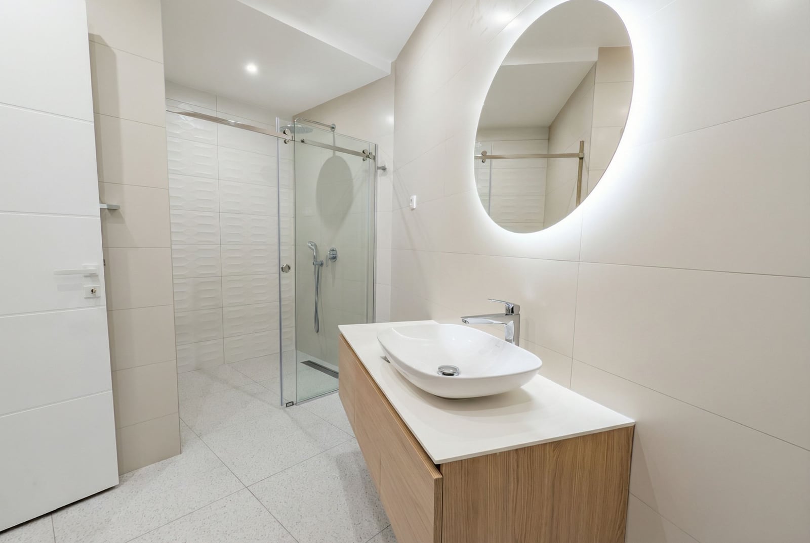 Modern bathroom in an apartment in Bečići, Montenegro: shower cabin, vanity with sink, and illuminated mirror.