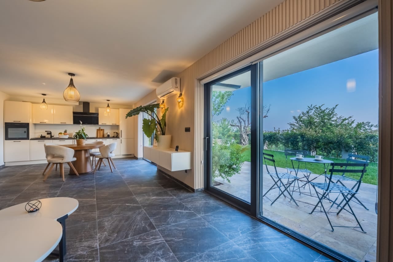 Modern living room with kitchen in a villa in Budva, Montenegro: panoramic windows, terrace with garden, and stylish interior.