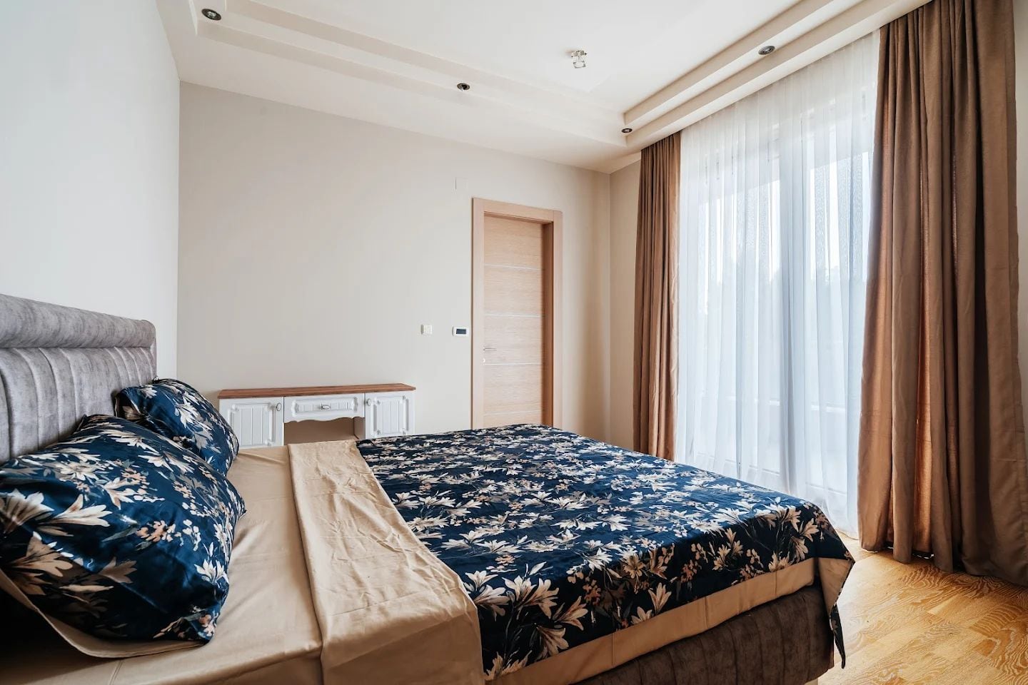 Bright bedroom with a double bed and a panoramic window in a modern apartment, Budva, Montenegro.