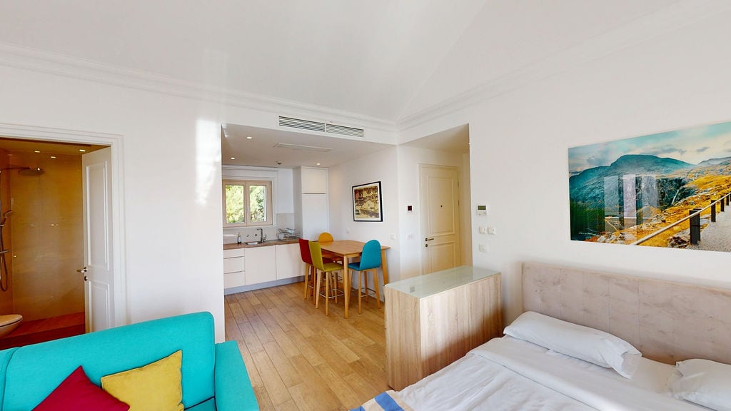 Modern living room with kitchen in an apartment in Luštica, Montenegro: double bed, bright sofa, and dining area.