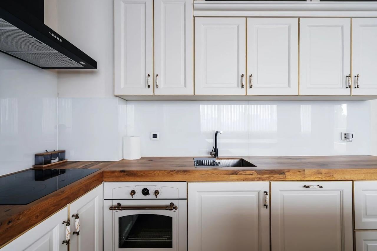 Modern white kitchen with a wooden countertop in an apartment, Budva, Montenegro. Built-in appliances and stylish design.