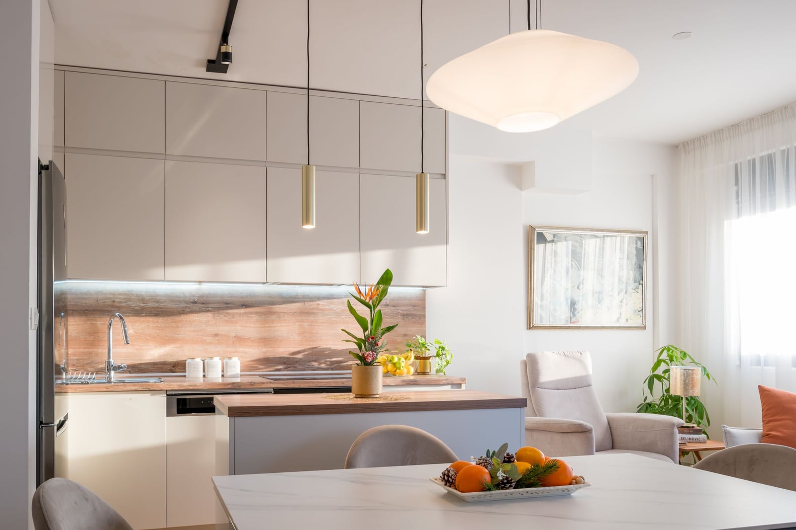 Modern kitchen-living room in a Tivat apartment, Montenegro: light-colored cabinetry, kitchen island, and dining area.