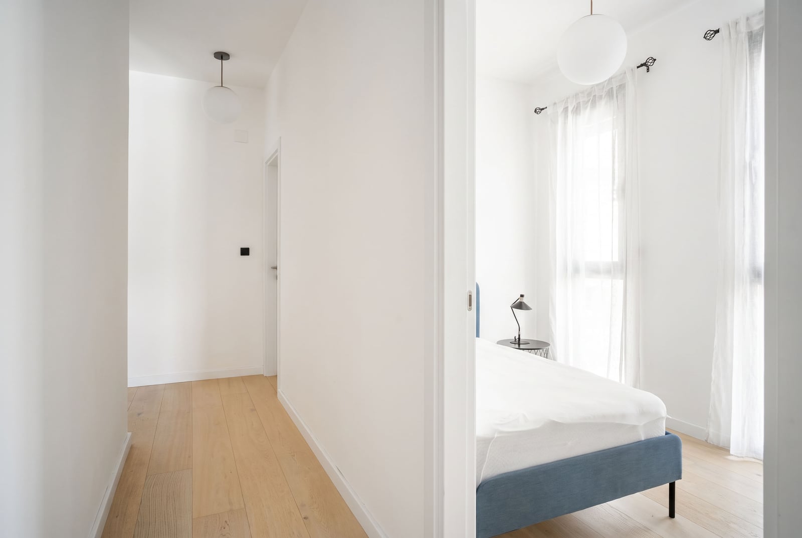 Bright apartment interior in Tivat, Montenegro: hallway with parquet flooring and entrance to a bedroom with white walls