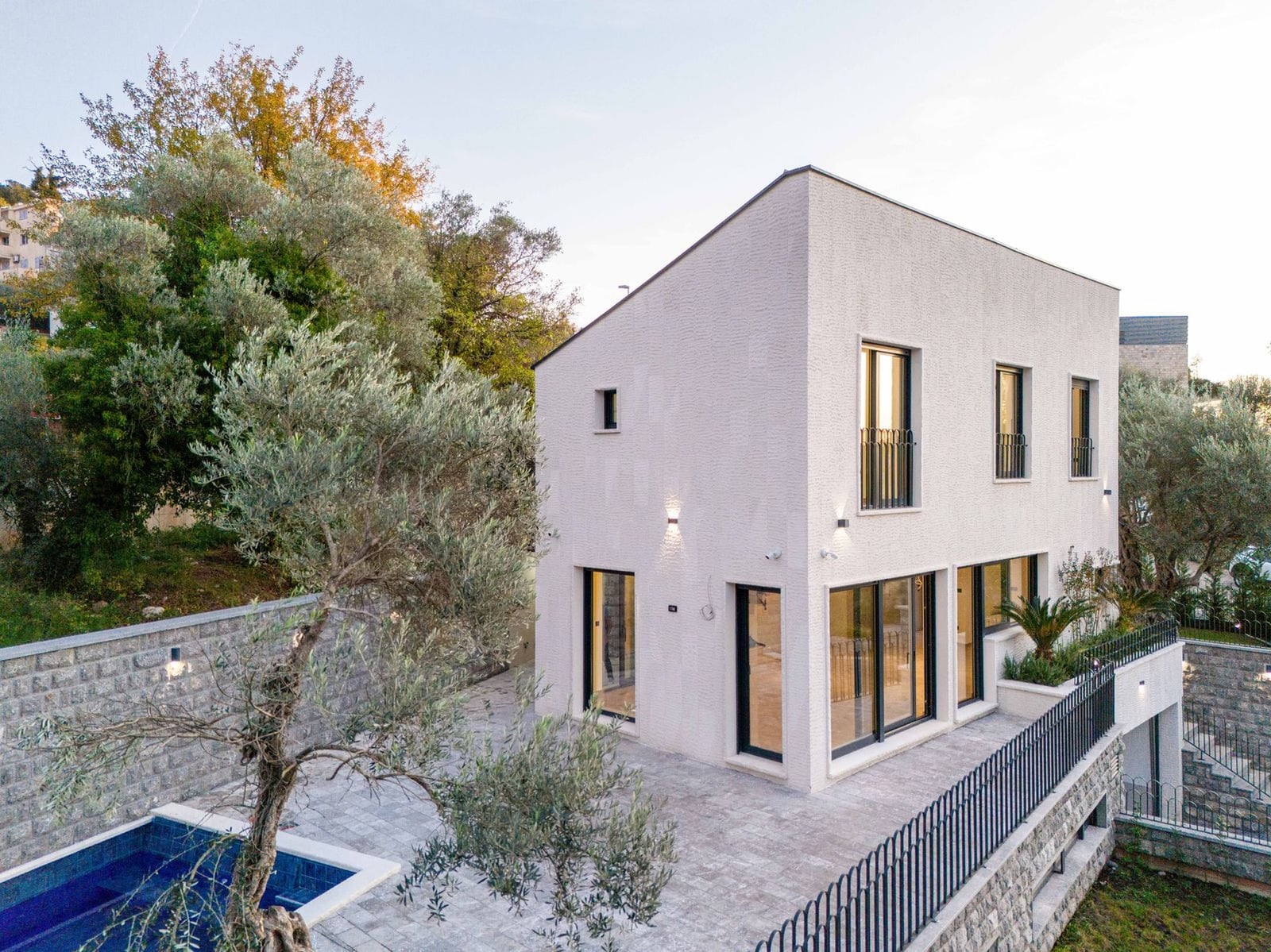 Modern two-story villa with a pool and terrace in Kamenovo, Montenegro: white stone facade and panoramic windows.