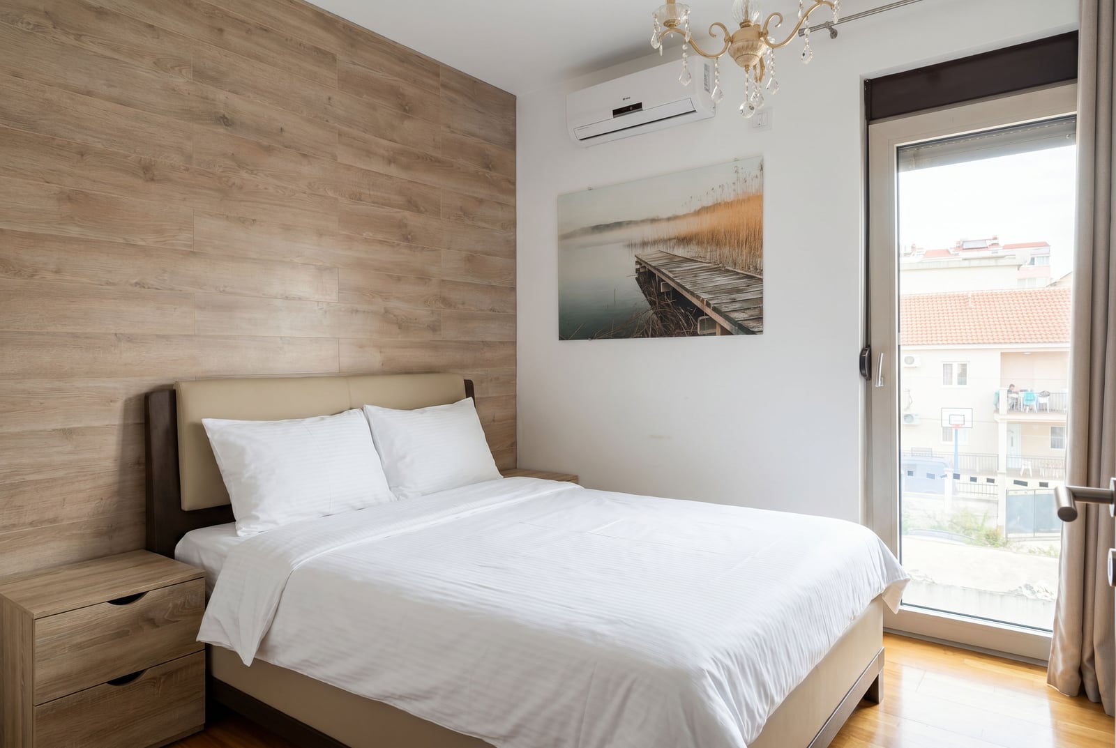 Cozy bedroom with a double bed and wood finishing in an apartment in Budva, Montenegro.