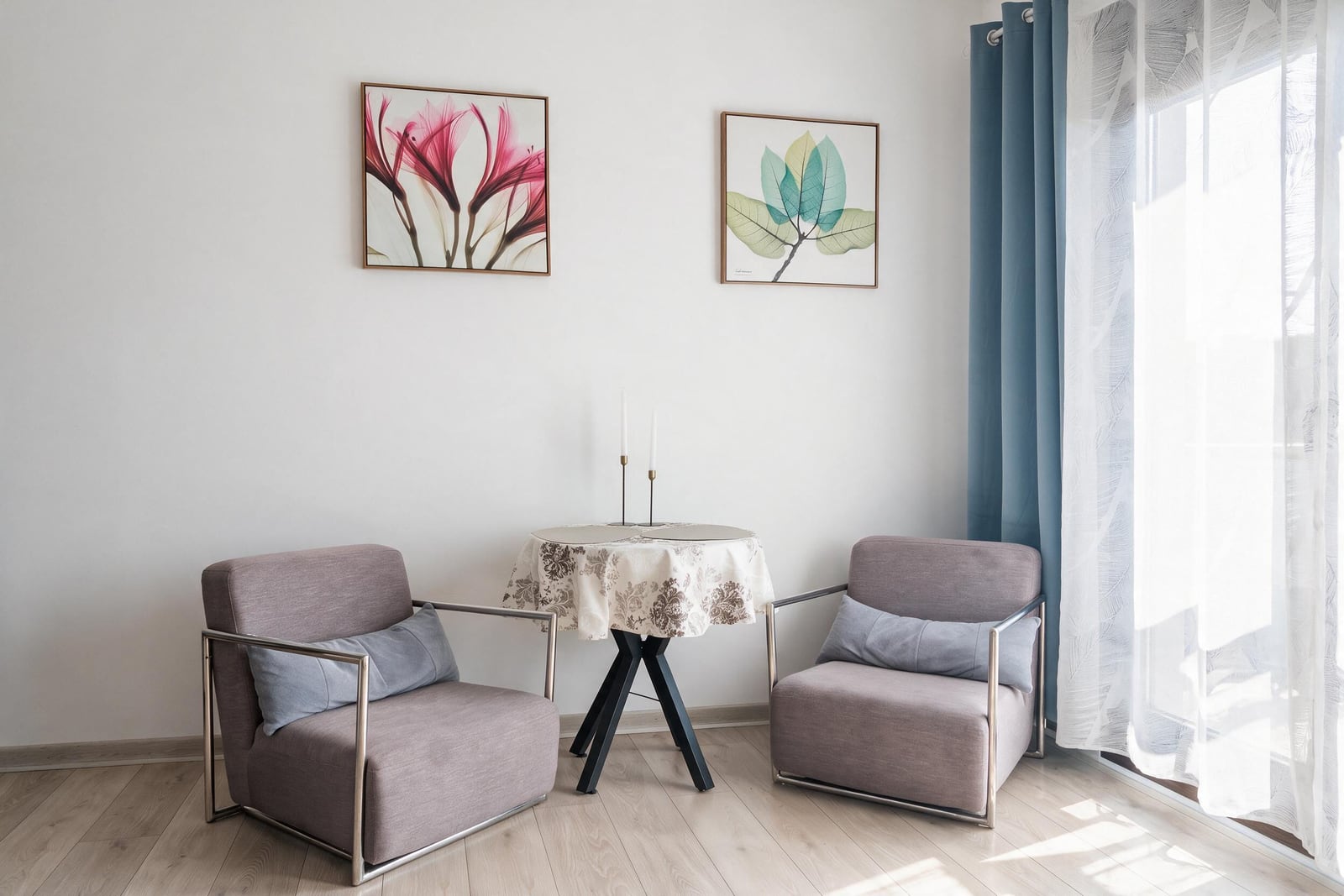 Cozy lounge area in the living room of an apartment in Budva, Montenegro: two armchairs, a round coffee table, and paintings on the wall.