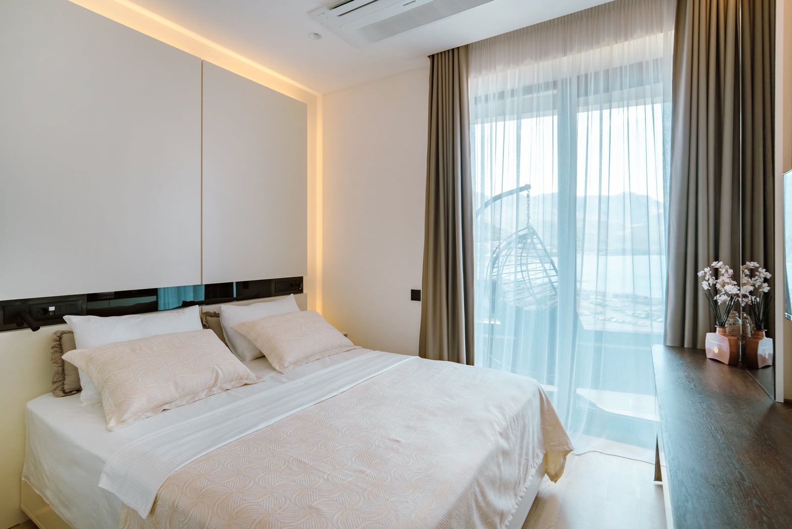 Modern bedroom with a double bed and sea view in the Bečići residential complex, Montenegro. Stylish interior, panoramic windows.