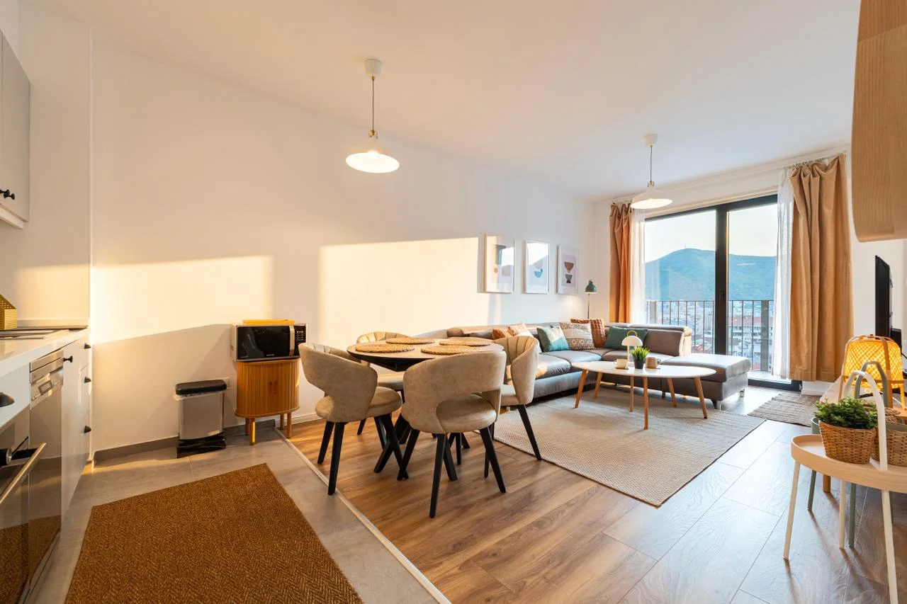 Open plan living room with sofa, dining table, and visible kitchen area in the foreground.