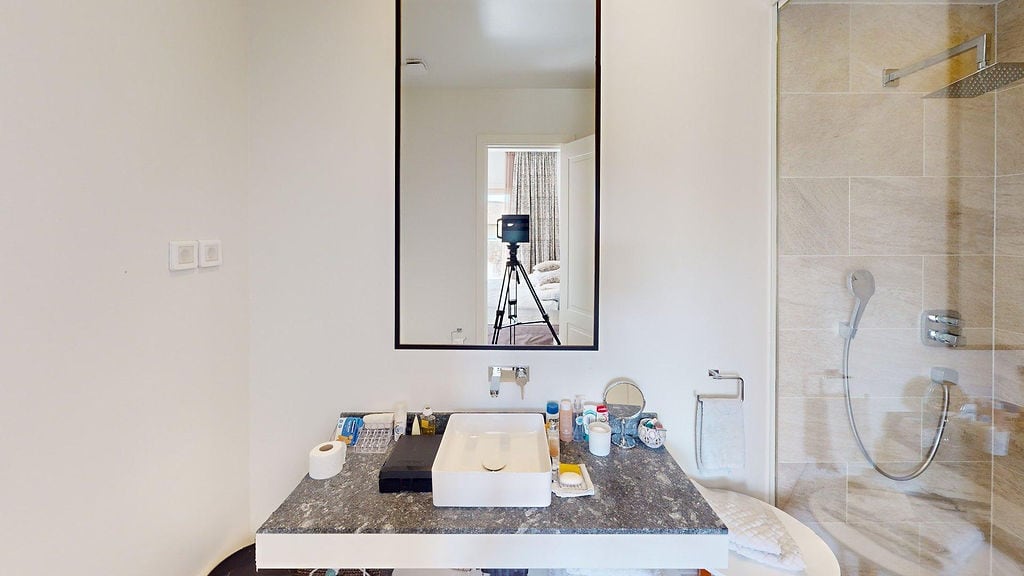 Modern bathroom in an apartment, Luštica, Montenegro: stone countertop, vessel sink, and shower cabin.