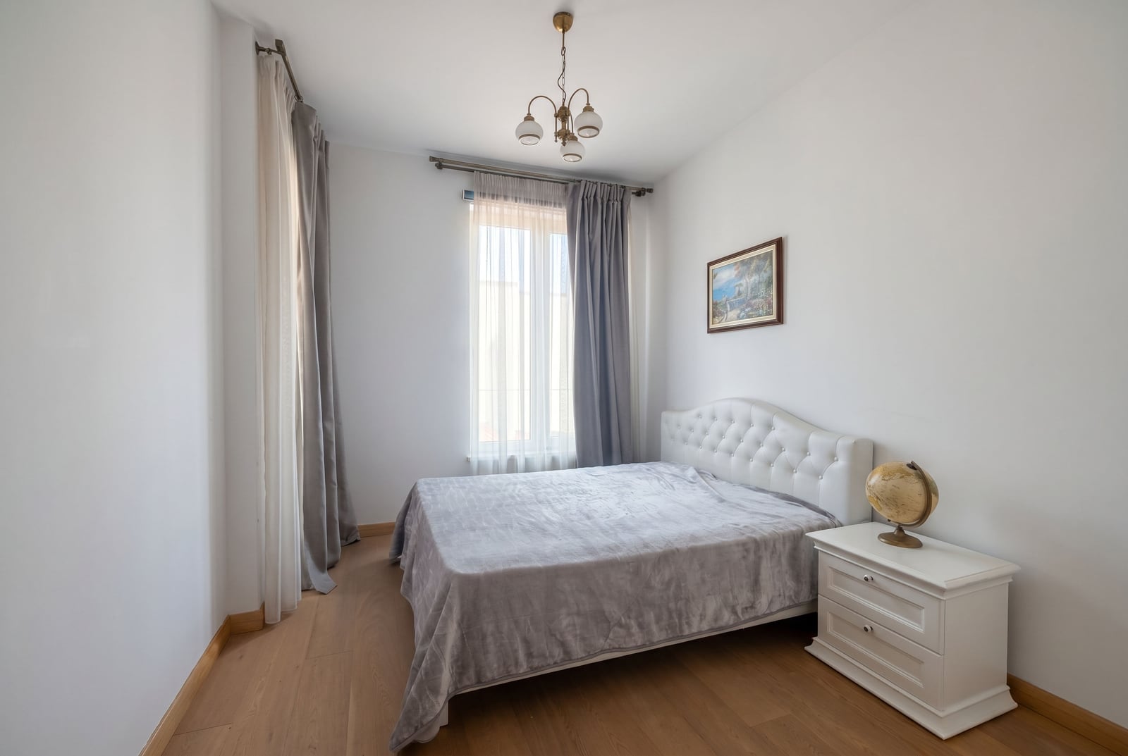 Bright bedroom with a double bed and a bedside table in an apartment in Budva, Montenegro. Modern interior with parquet flooring.