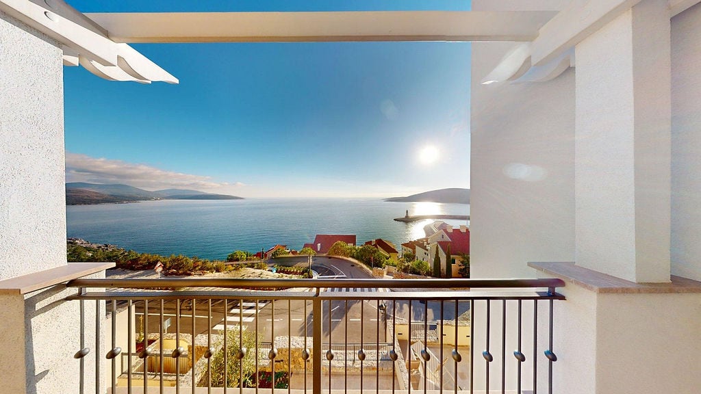 View from the balcony of an apartment in Luštica Bay, Montenegro: panorama of the Adriatic Sea, the promenade, and the mountains on a sunny day.