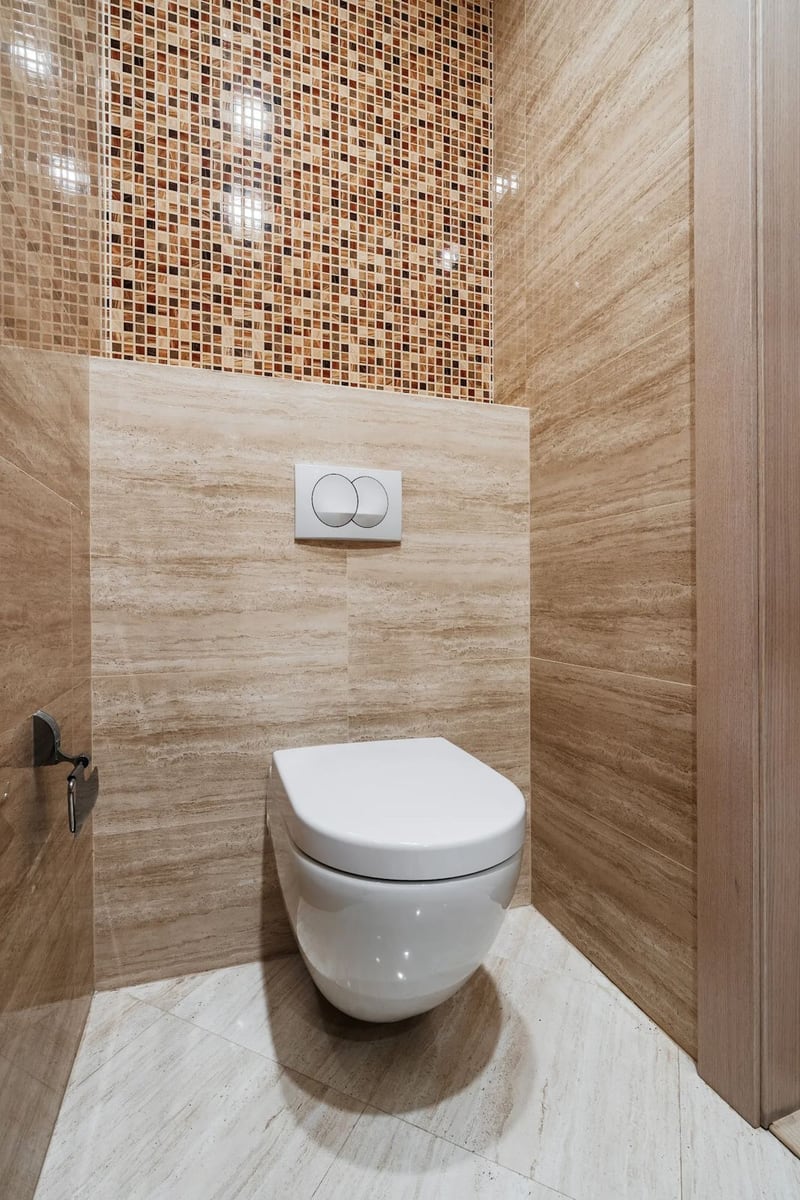 Modern bathroom with a wall-mounted toilet and beige tile and mosaic finishes in an apartment, Budva, Montenegro.