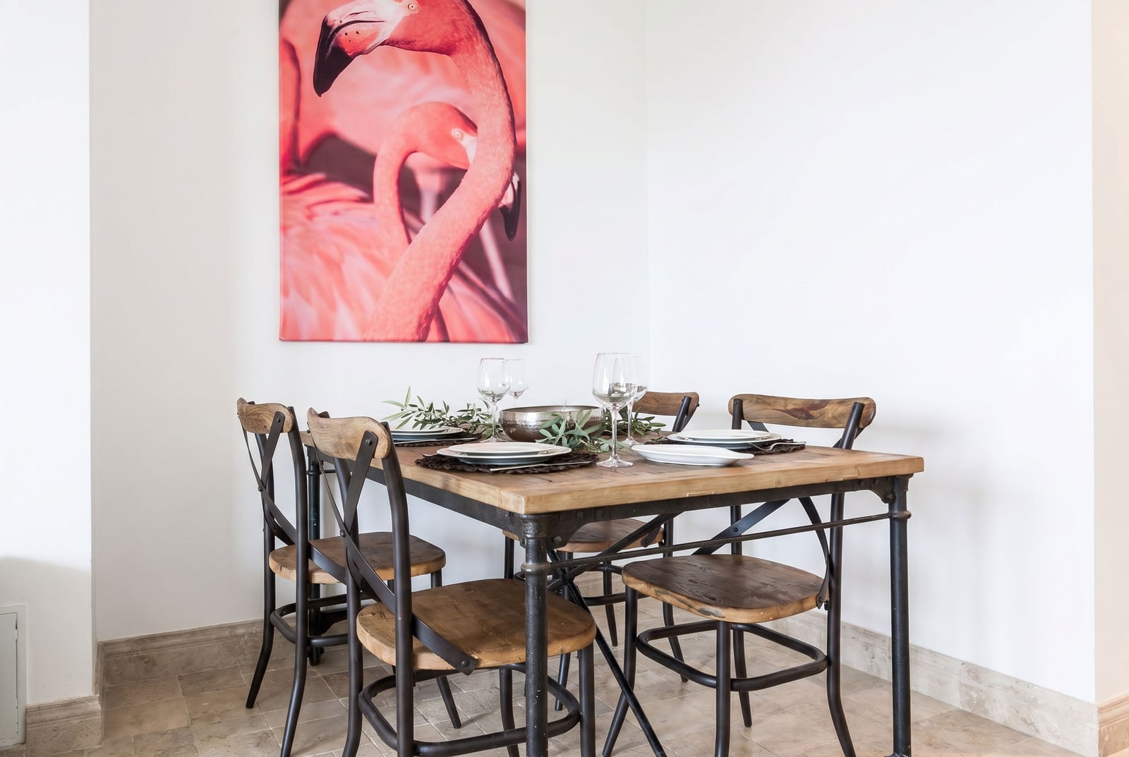 Dining area in an apartment in Risan, Montenegro: a wooden loft-style table, chairs, and a painting with flamingos.
