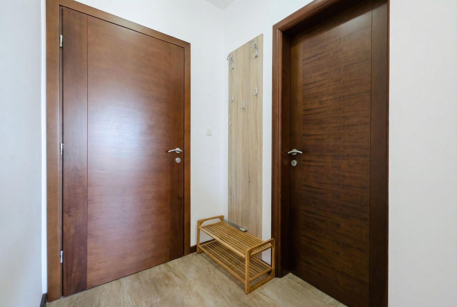 Hallway in an apartment in Tivat, Montenegro: dark wood interior doors, a coat rack, and a shoe shelf.