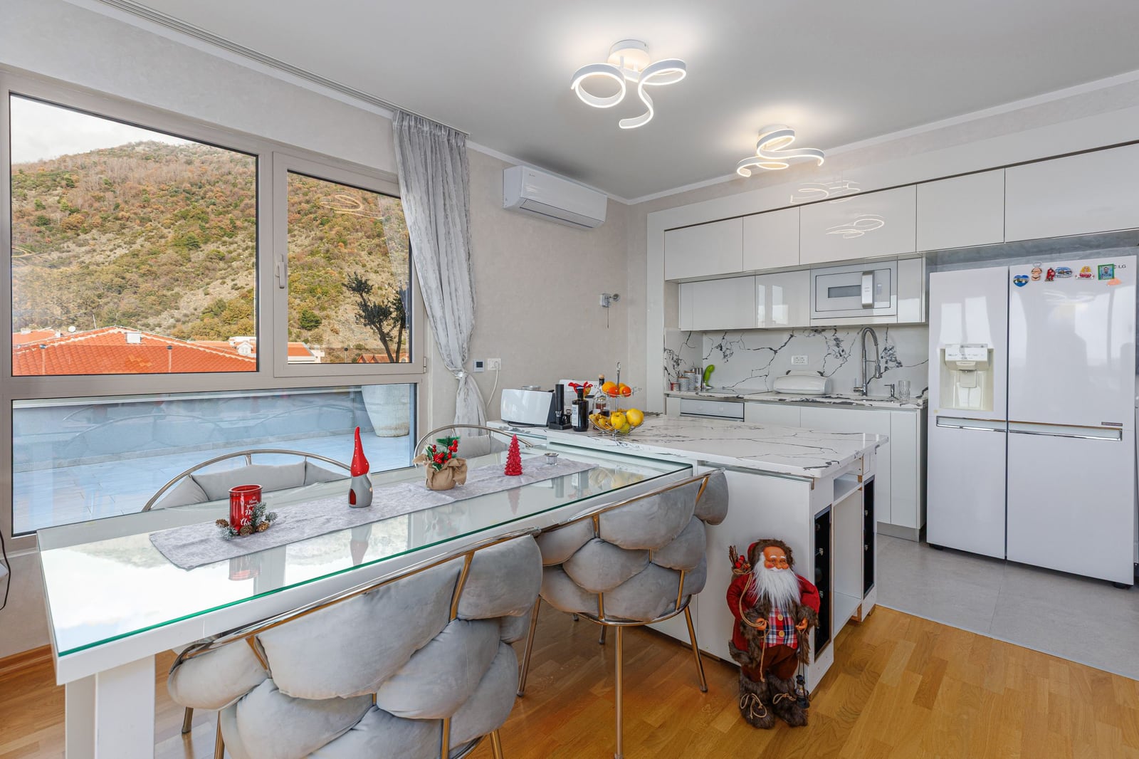 Modern open-plan kitchen and living room with a marble island in a penthouse, Bečići, Montenegro: mountain views and stylish interior.