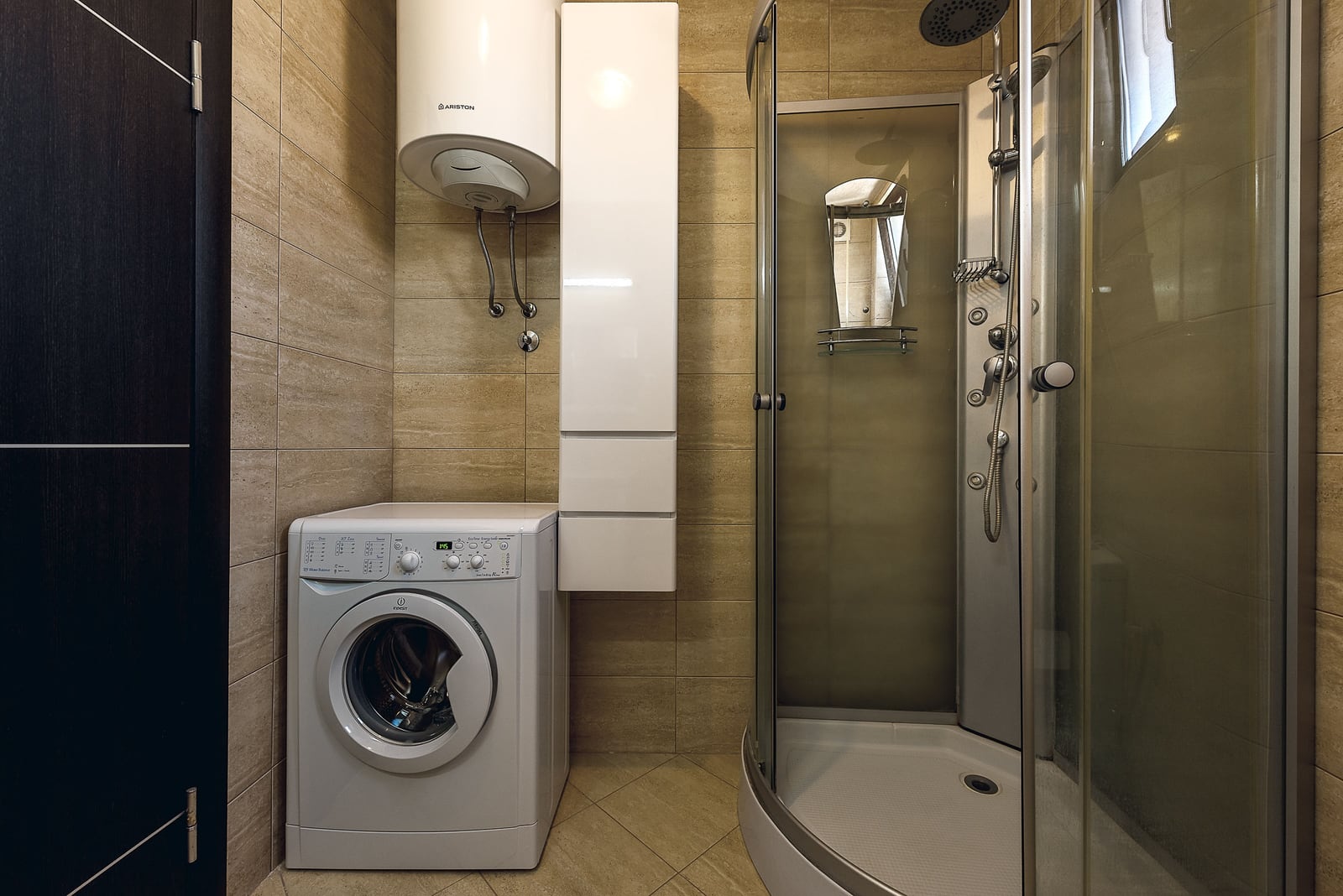 Bathroom in an apartment in Budva, Montenegro: shower cabin, washing machine, and Ariston water heater on the wall.