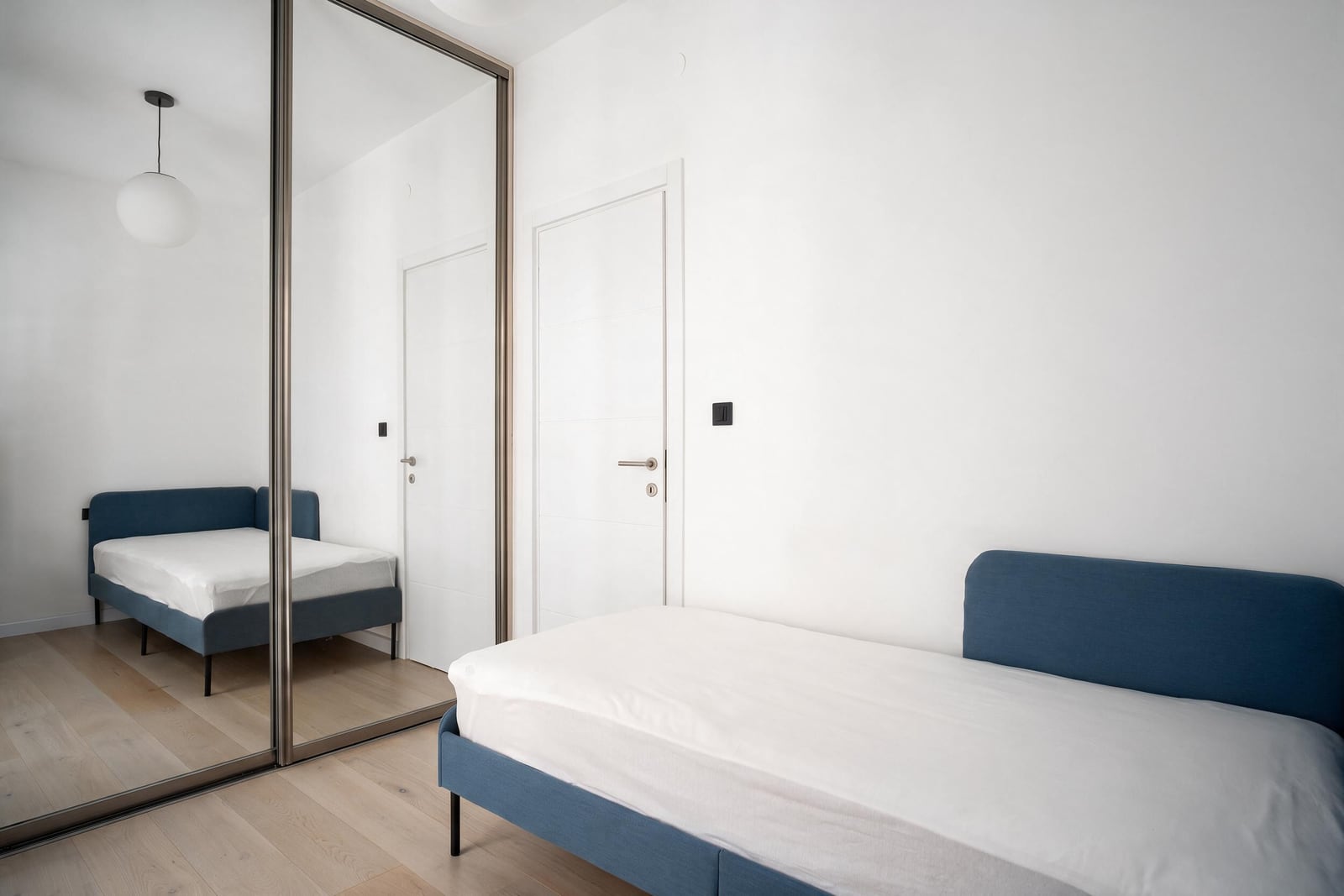 Modern bedroom with a blue bed and a large mirrored wardrobe in an apartment in Tivat, Montenegro
