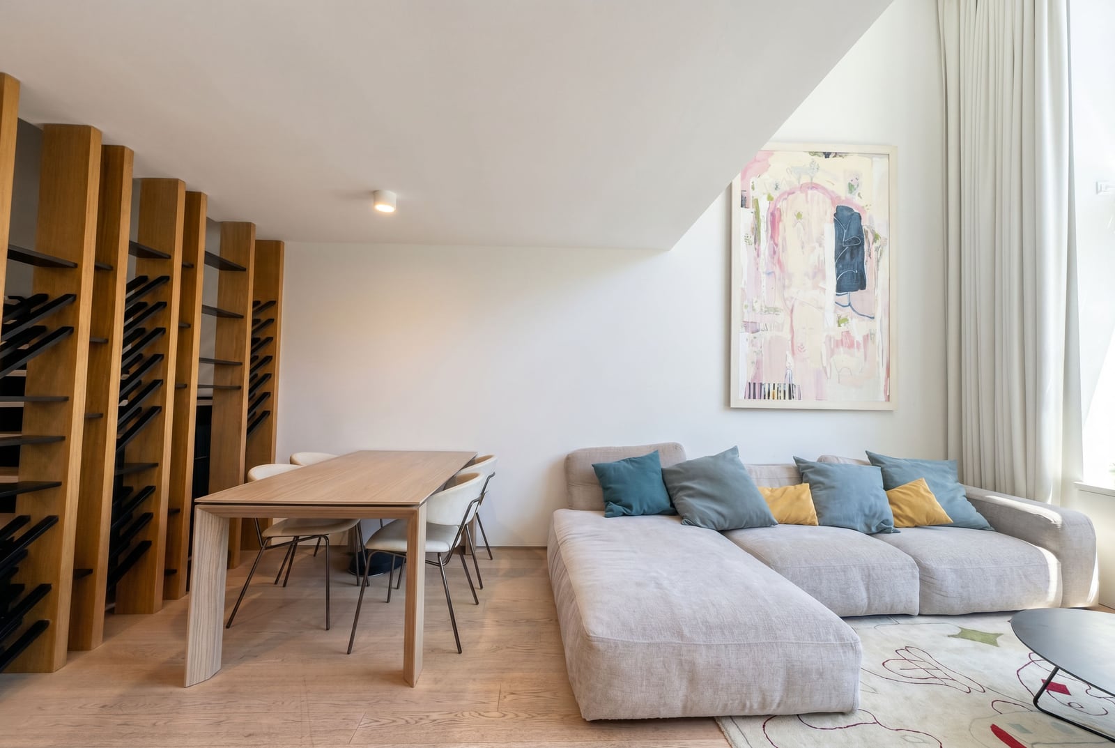 Modern living room in a Budva apartment, Montenegro: plush sofa, dining table, designer shelving unit, and decor.