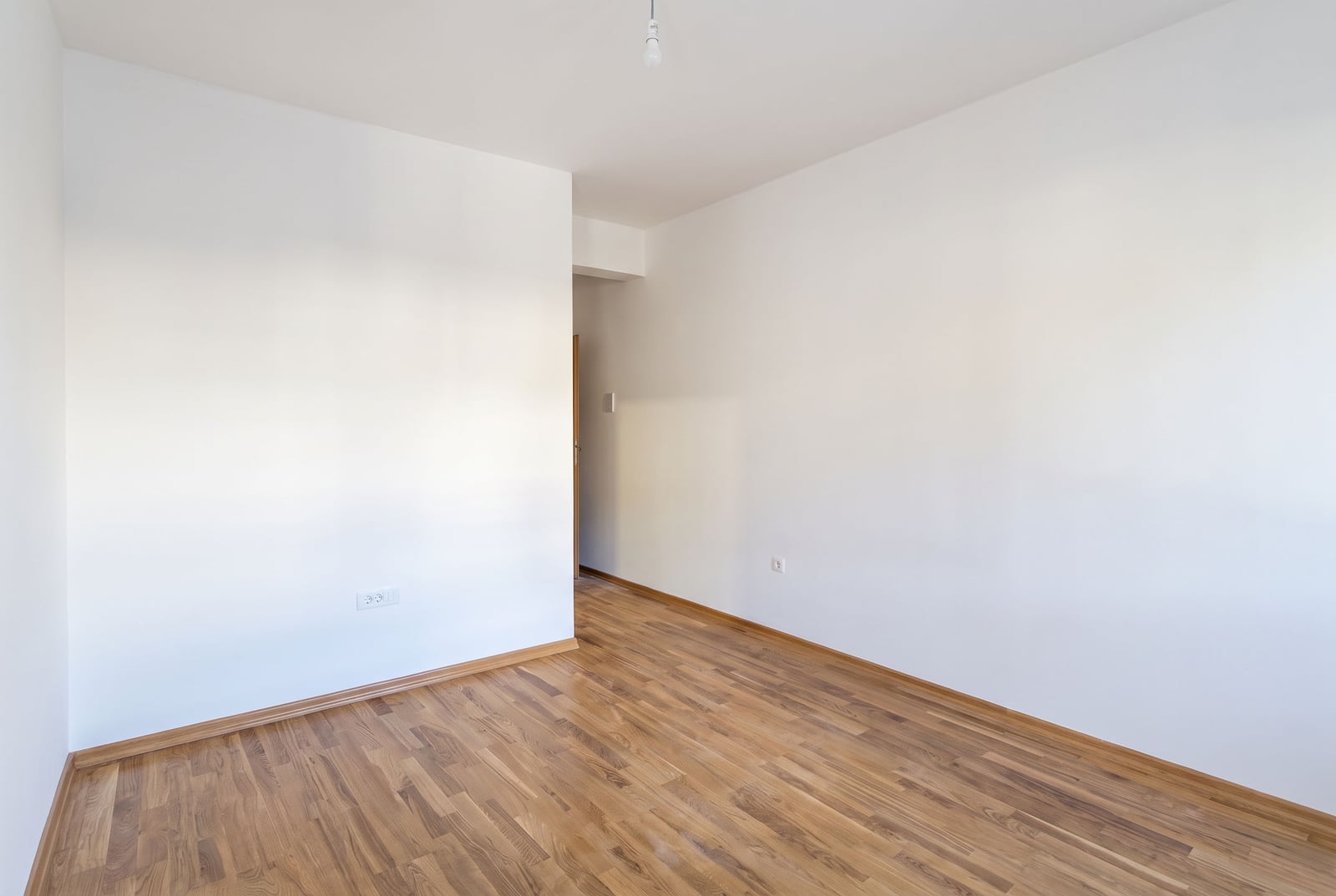 Empty bedroom with white walls and parquet flooring in an apartment in Budva, Montenegro