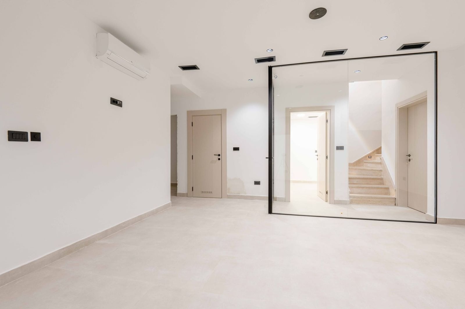 Modern living room with white finishes, glass partition, and staircase in a villa in Kamenovo, Montenegro.