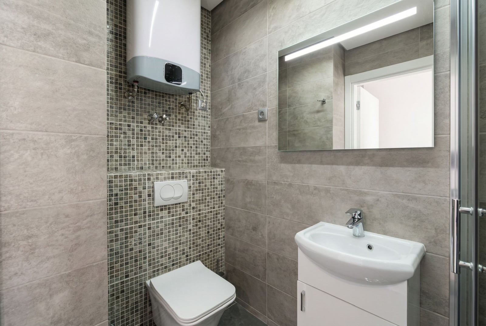 Modern bathroom in an apartment in Bečići, Montenegro: tile, wall-mounted toilet, sink, and water heater.