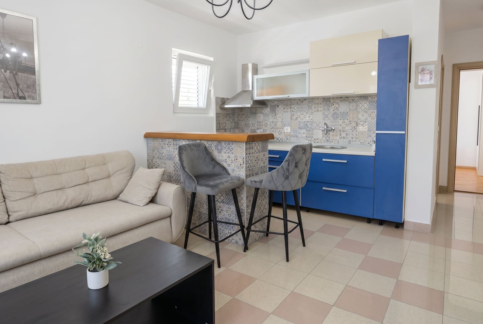 Kitchen-living room with a bar counter in an apartment in Budva, Montenegro: modern furniture, patterned tile, and a bright interior.