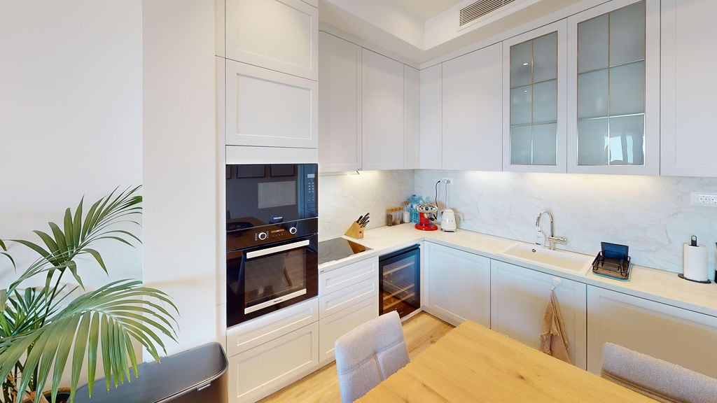 Modern white kitchen with Miele appliances in an apartment, Luštica, Montenegro: bright interior, dining area, and decor.