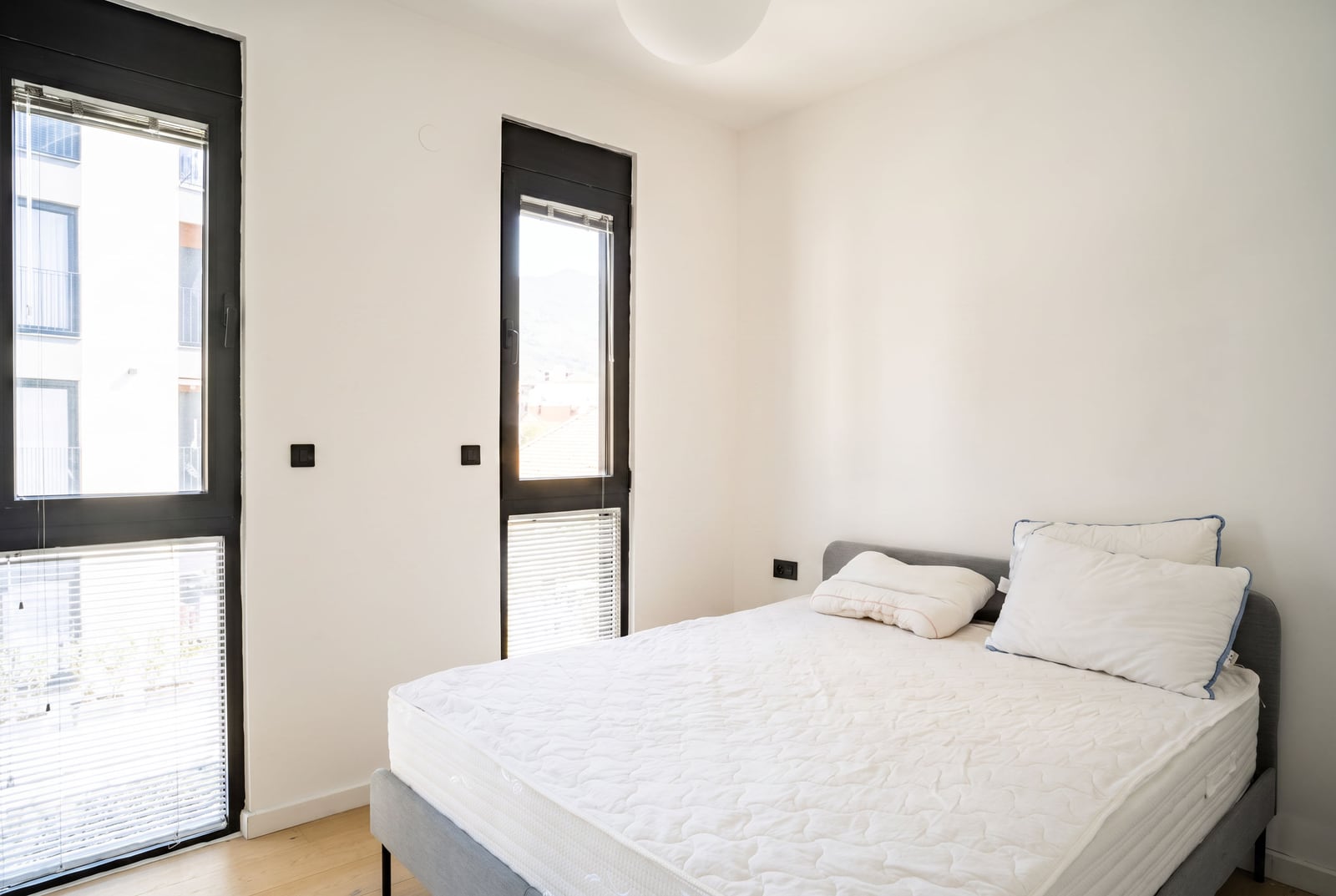 Bright bedroom with a double bed and panoramic windows in an apartment in Tivat, Montenegro.