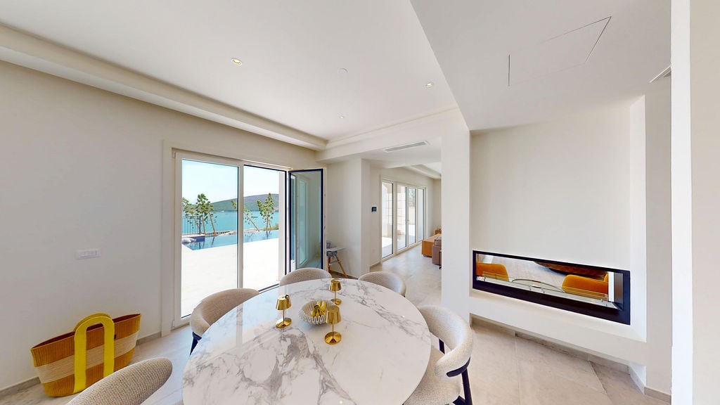 Modern living room with a marble table and fireplace in a luxury villa, Luštica, Montenegro, sea and pool view.