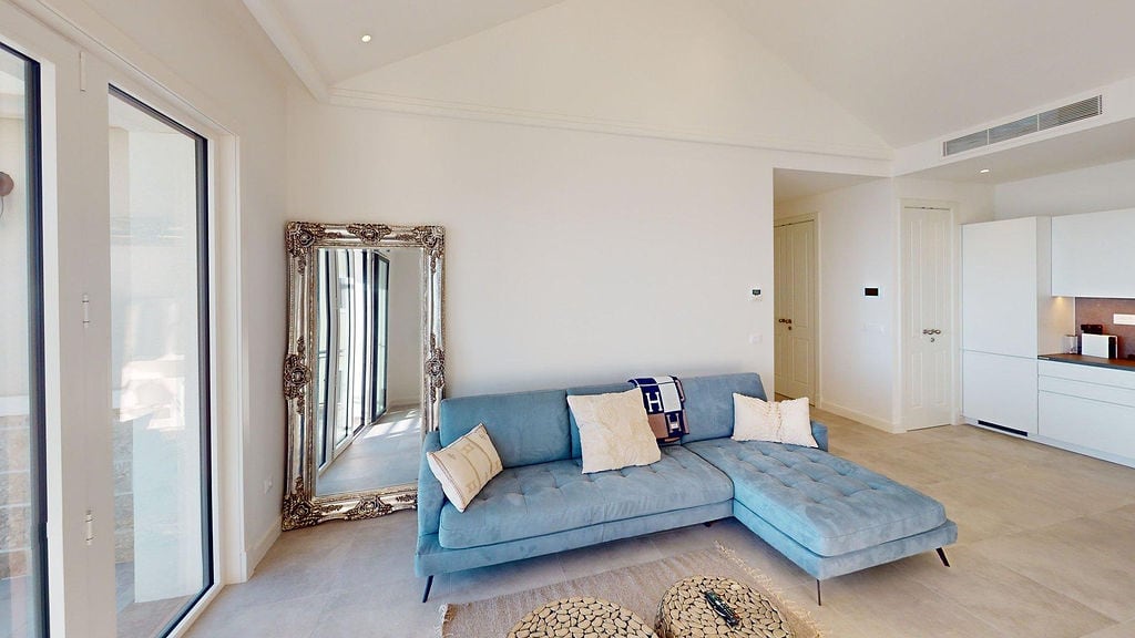 Modern living room with a blue sofa and mirror in an apartment in Luštica, Montenegro. Bright interior with a kitchen.