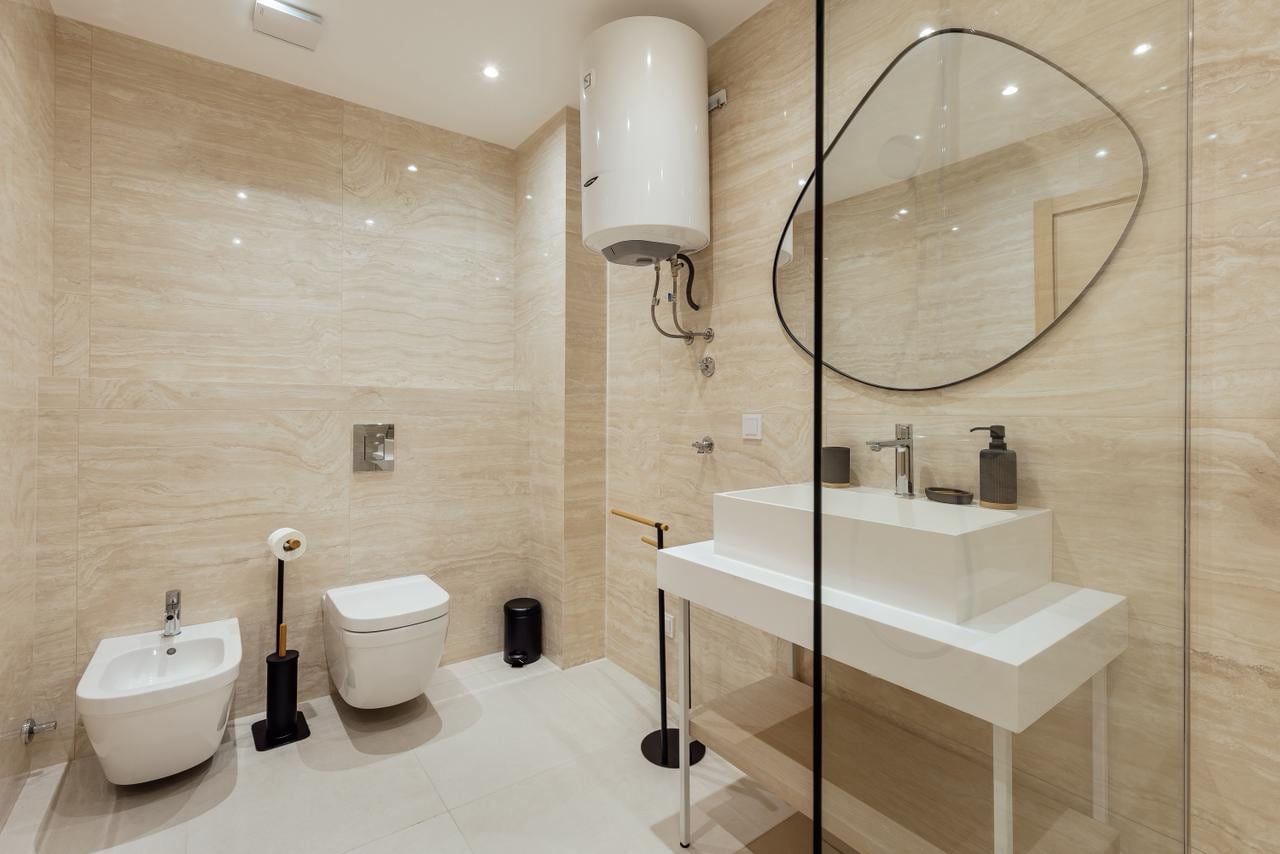 Modern bathroom in an apartment in Igalo, Montenegro: beige tiles, a walk-in shower, and a stylish mirror.