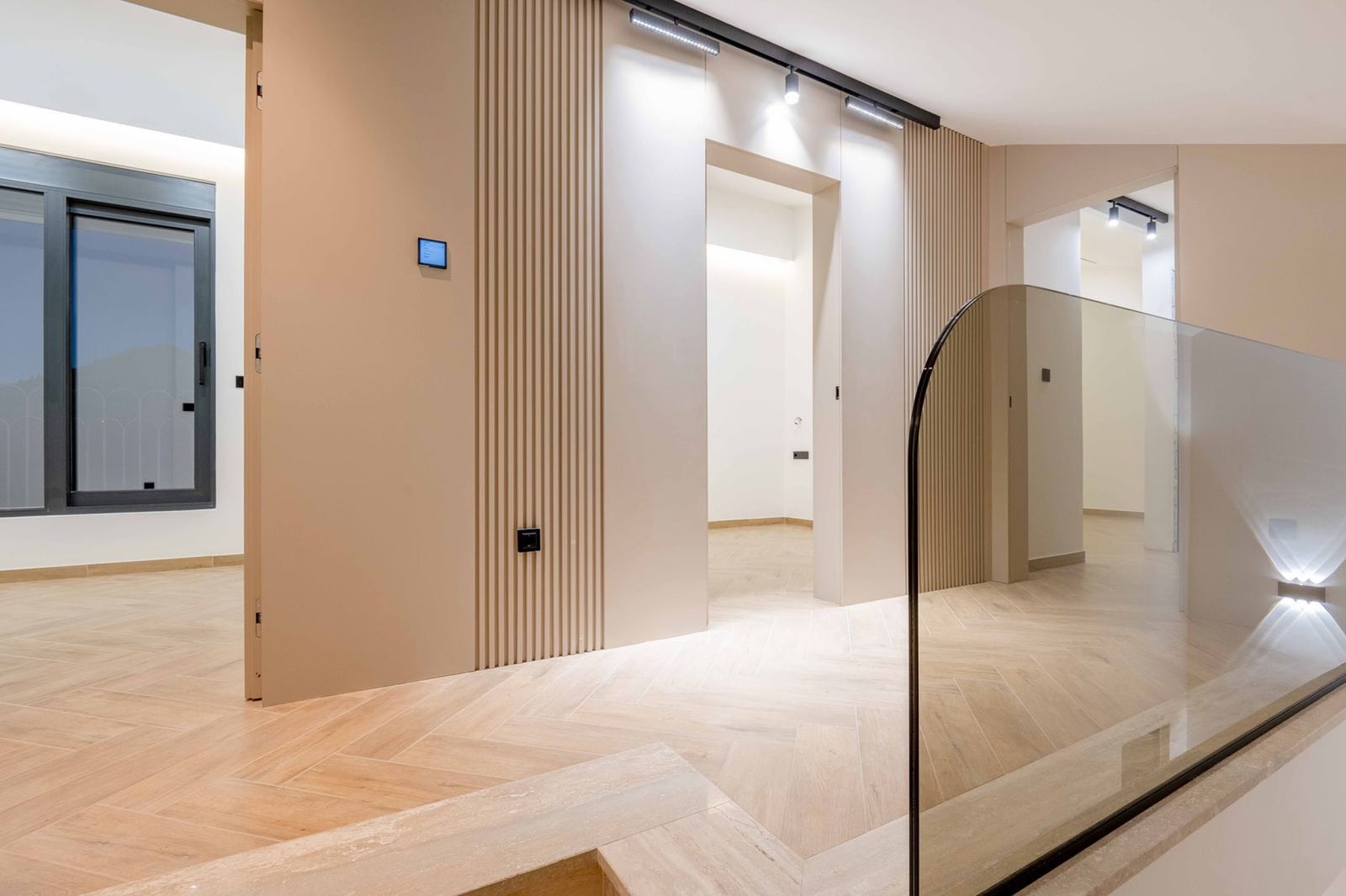 Modern interior of a villa in Kamenovo, Montenegro: living room with slatted panels, glass railing, and parquet flooring.