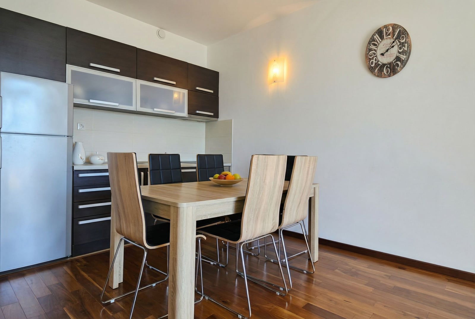 Modern kitchen-dining room in an apartment in Tivat, Montenegro: dark cabinetry, dining table, and wooden floor.