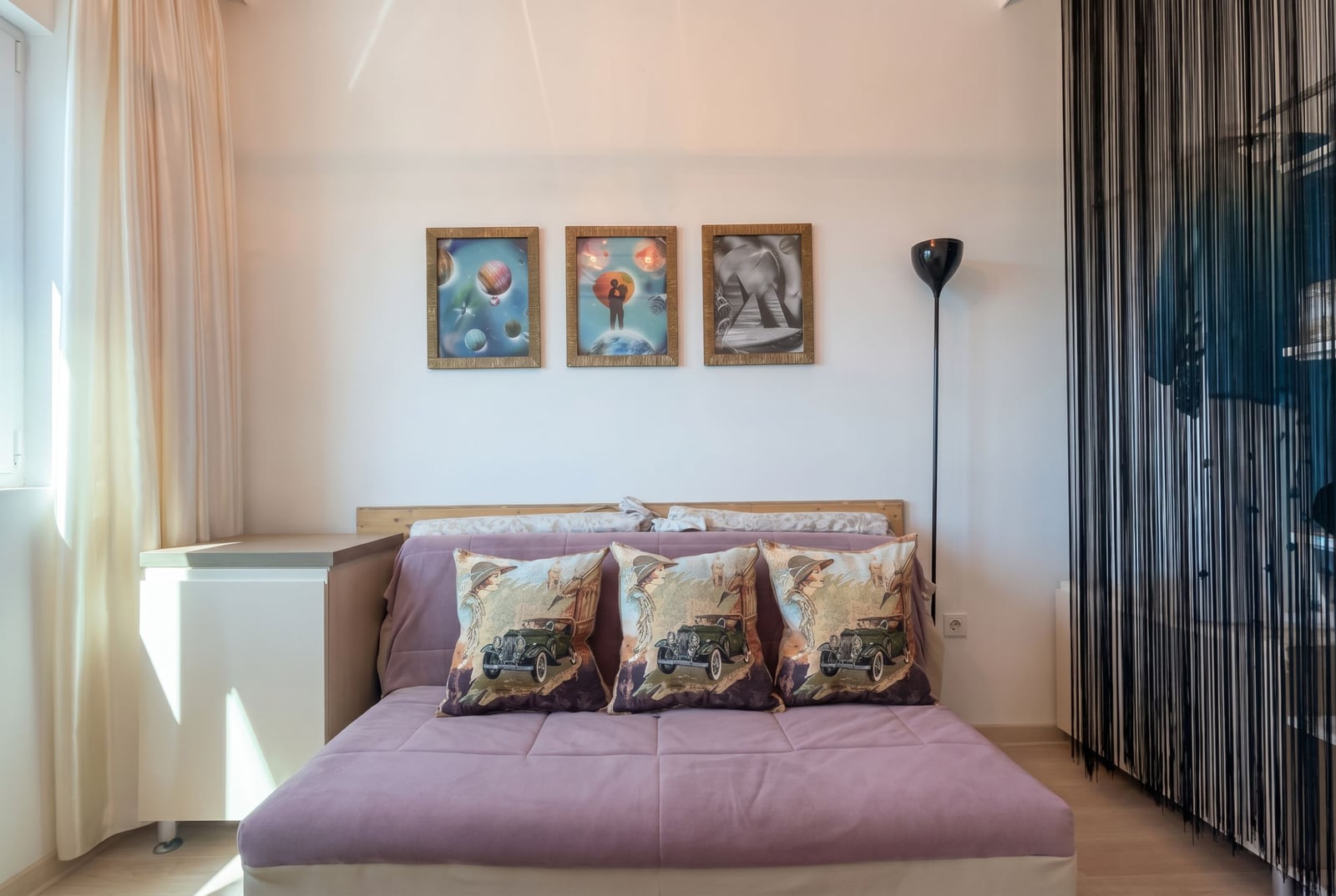 Bedroom in an apartment in Bečići, Montenegro: a pink sofa, decorative pillows, wall art, and a stylish floor lamp.
