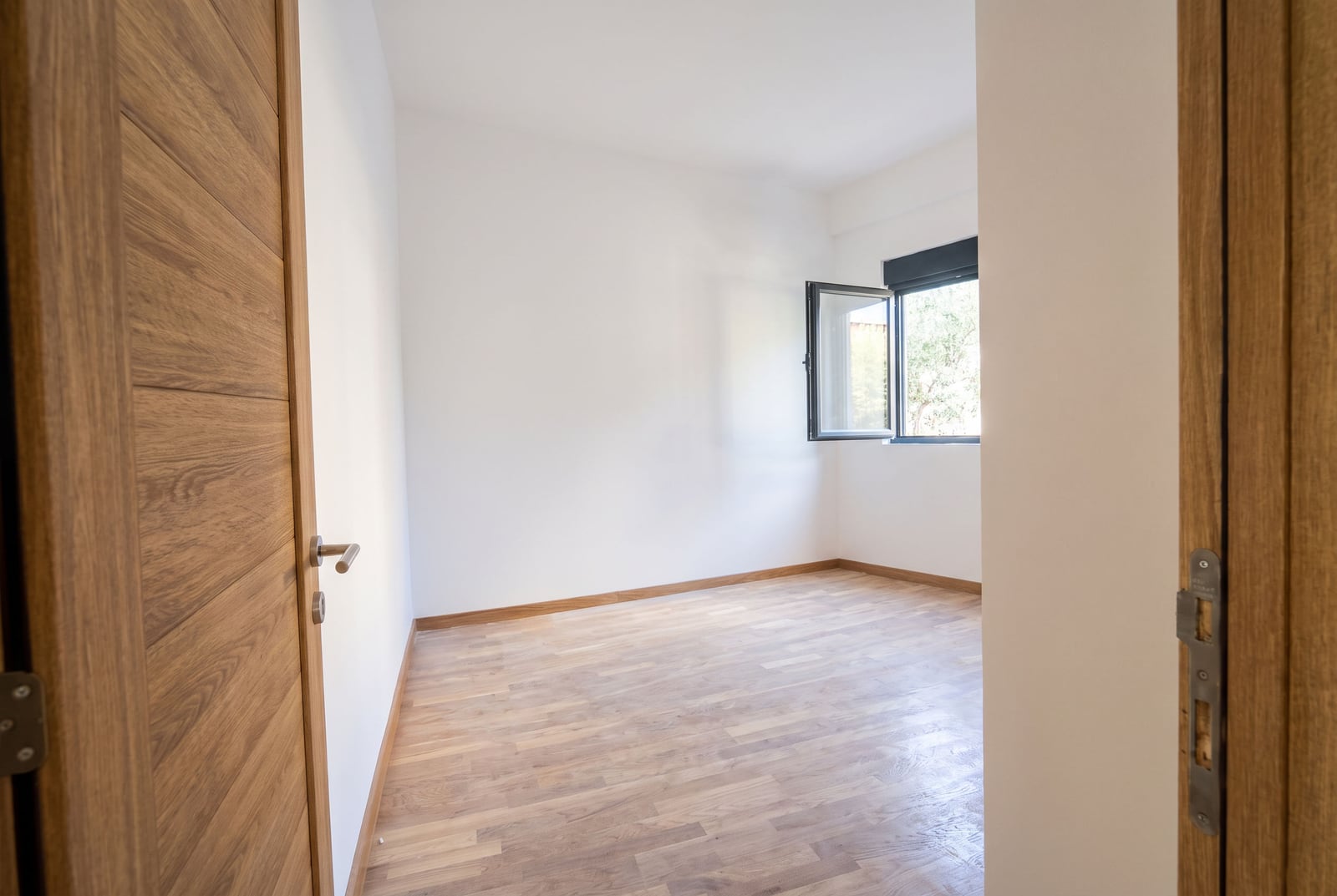 Bright empty bedroom with parquet flooring and white walls in an apartment in the city of Bar, Montenegro.